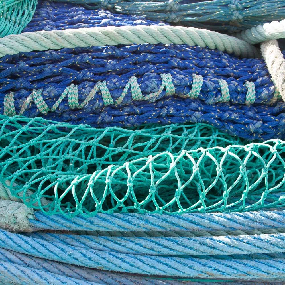 A pile of various blue and teal fishing ropes and nets.