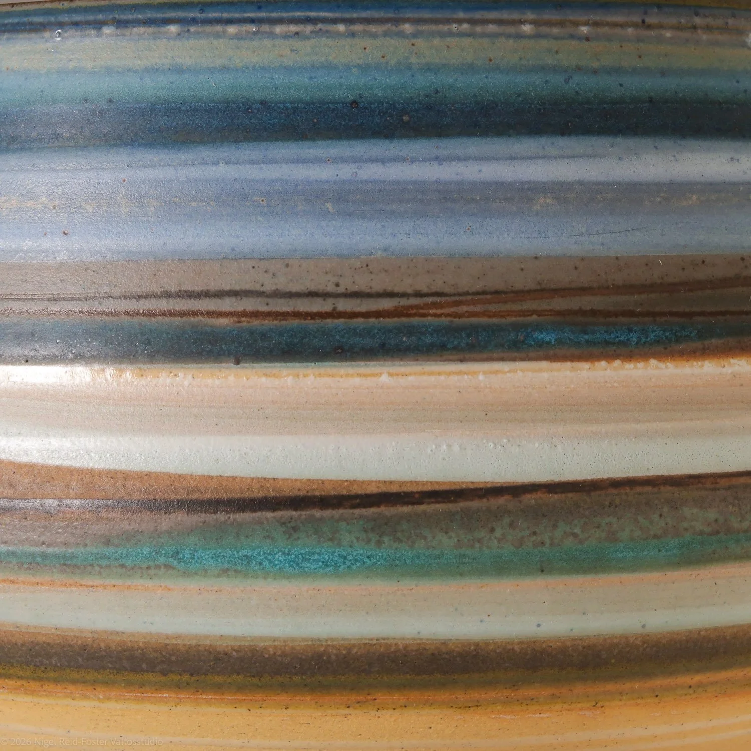 Close-up of a colorful, layered ceramic surface with shades of turquoise, blue, brown, white, and green.