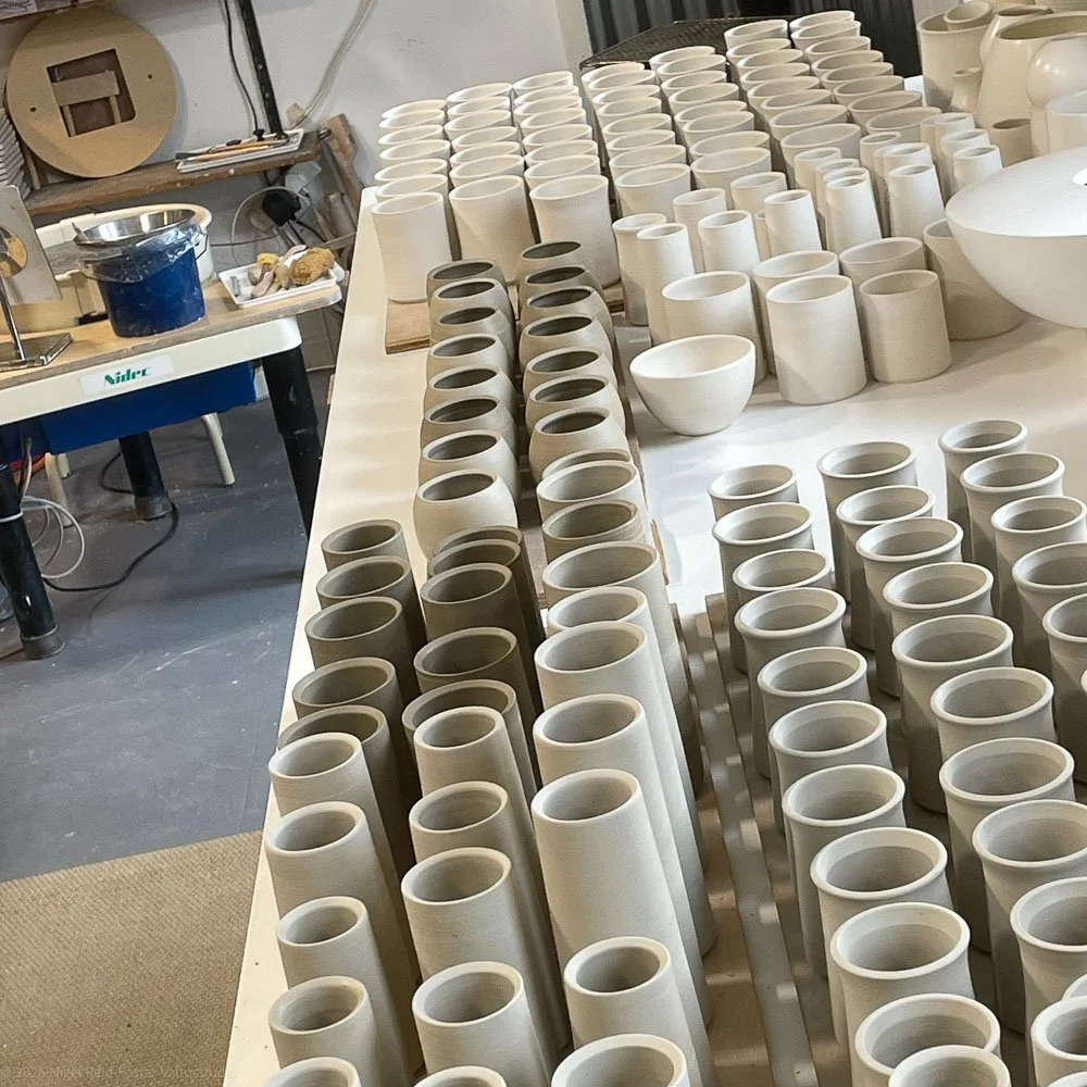 Unfinished pottery vessels organised on a worktable in a pottery studio.