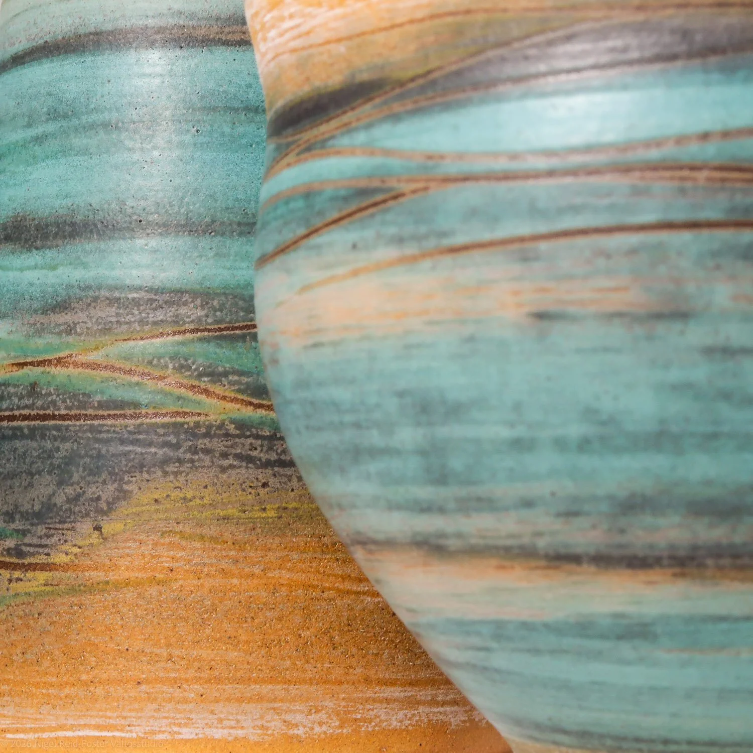 Close-up of two pottery vases with a swirl pattern, painted in turquoise, gray, and orange tones.