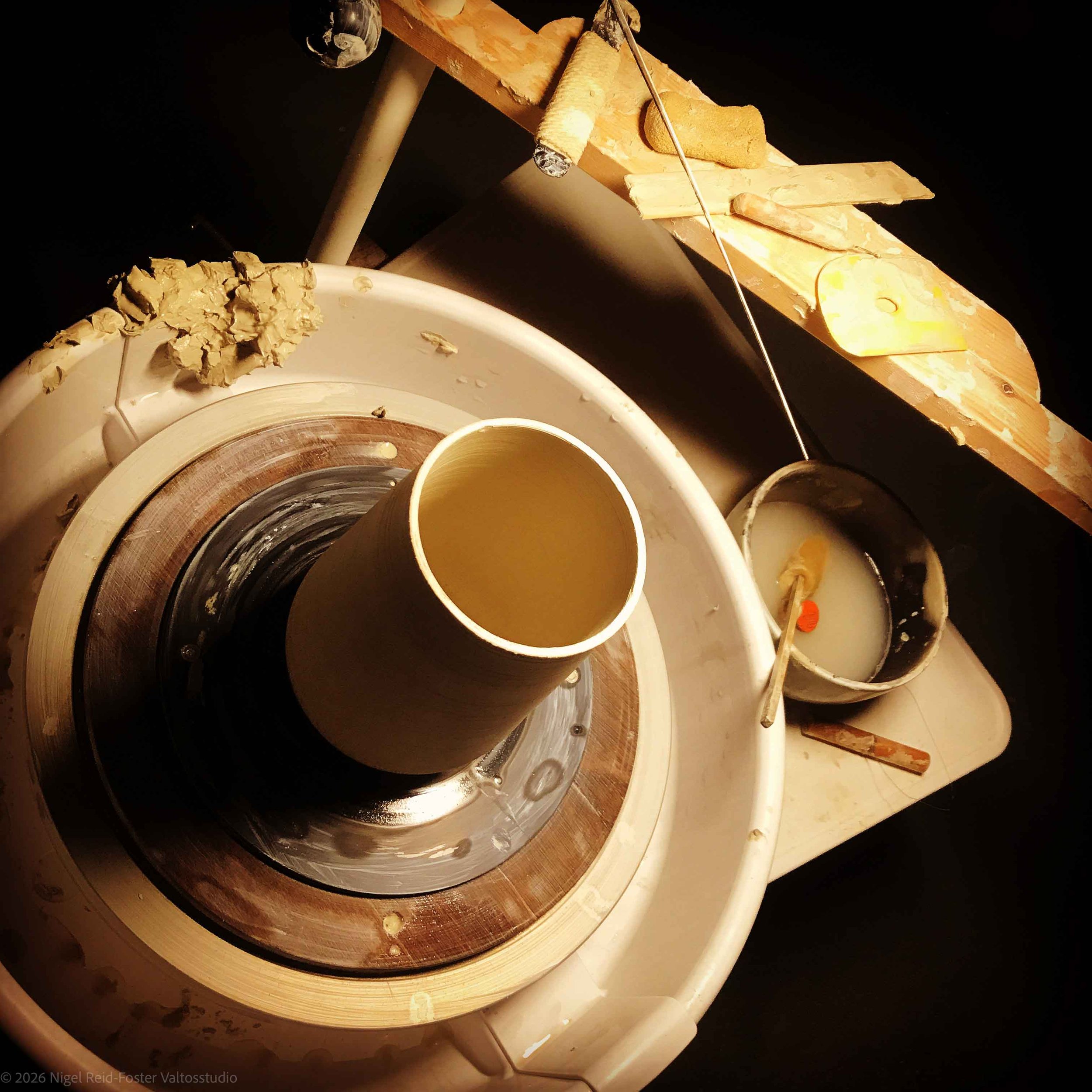 Atmospheric picture looking down at a potter's wheel with an unfinished pot sitting on it