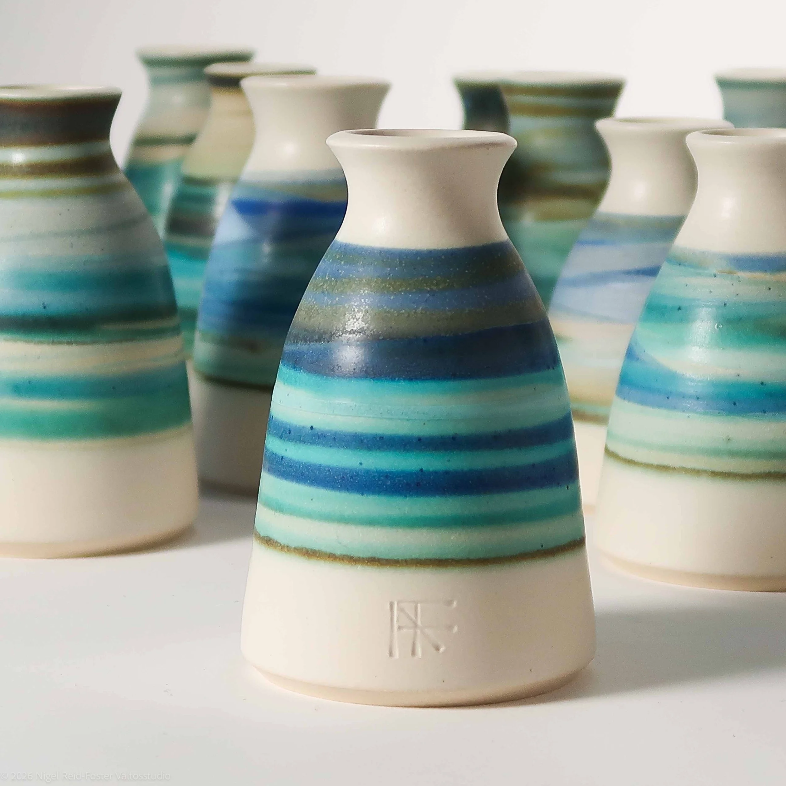 Collection of small bottle forms light sandy clay overlayed with aqua, blue and Turquoise glazes, satin and matt finish with a tactile surface