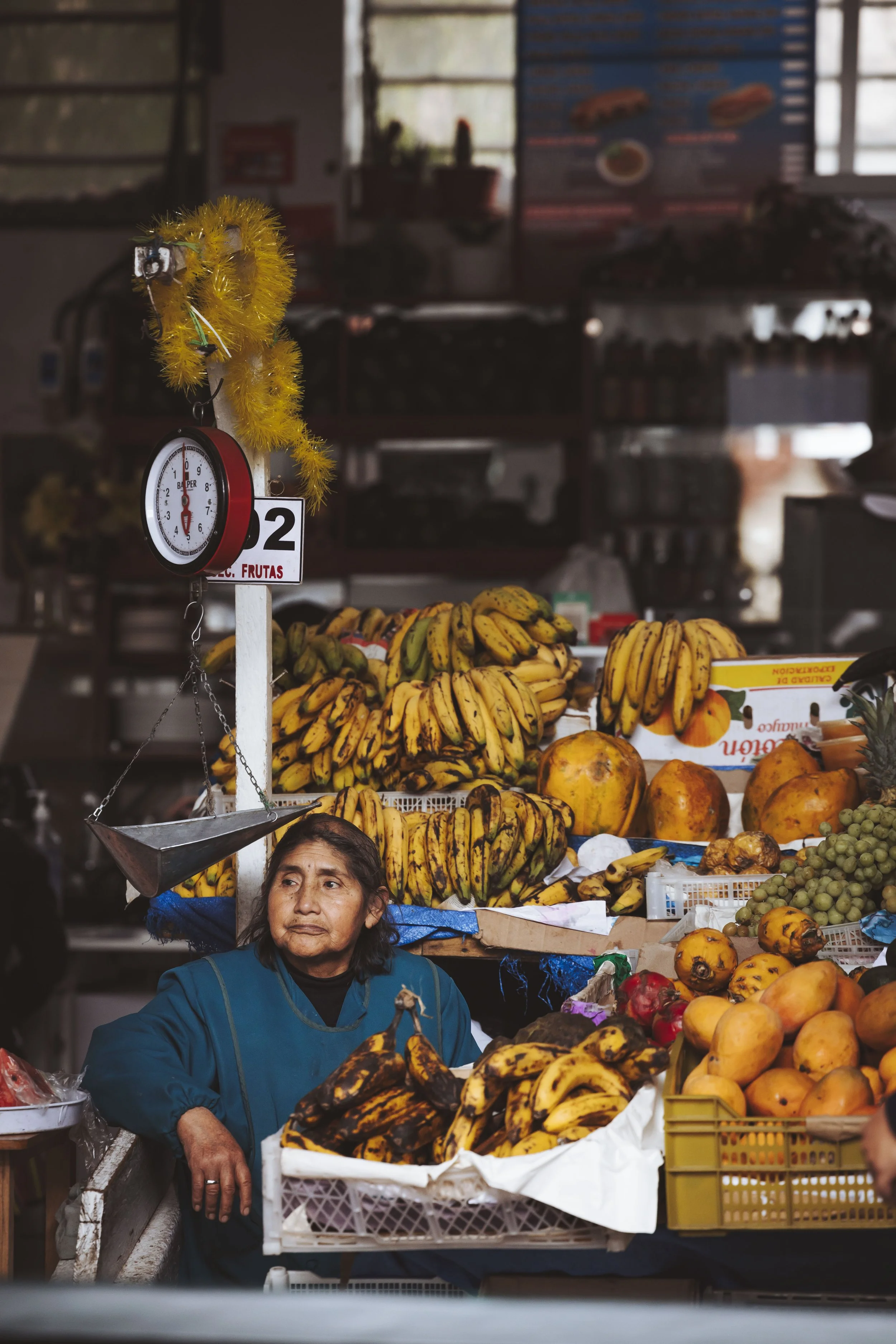 Frau verkauft Bananen, Papayas und Trauben an einem Marktstand.