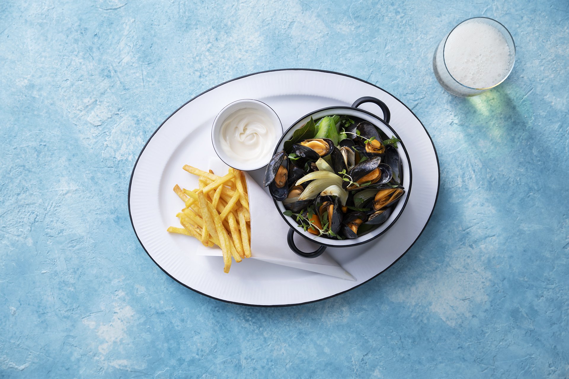 Pilzpfanne mit Pommes, Mayonnaise und einem Glas Milch auf blauem Hintergrund.