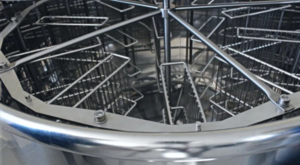 Inside a circular metal commercial dishwasher with racks for dishes and utensils.
