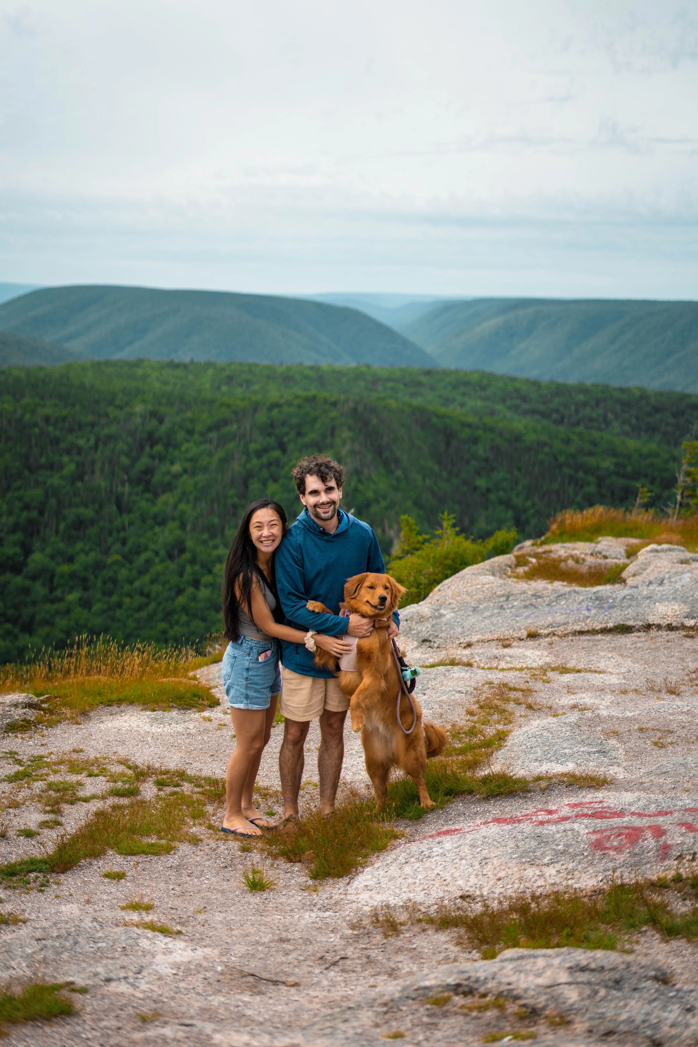 Couple enjoying a scenic lookout over forested hills during a Cape Breton outdoor adventure.
