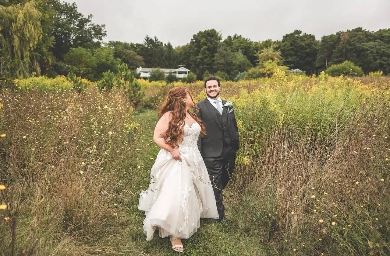 Bride and groom walking together through a meadow