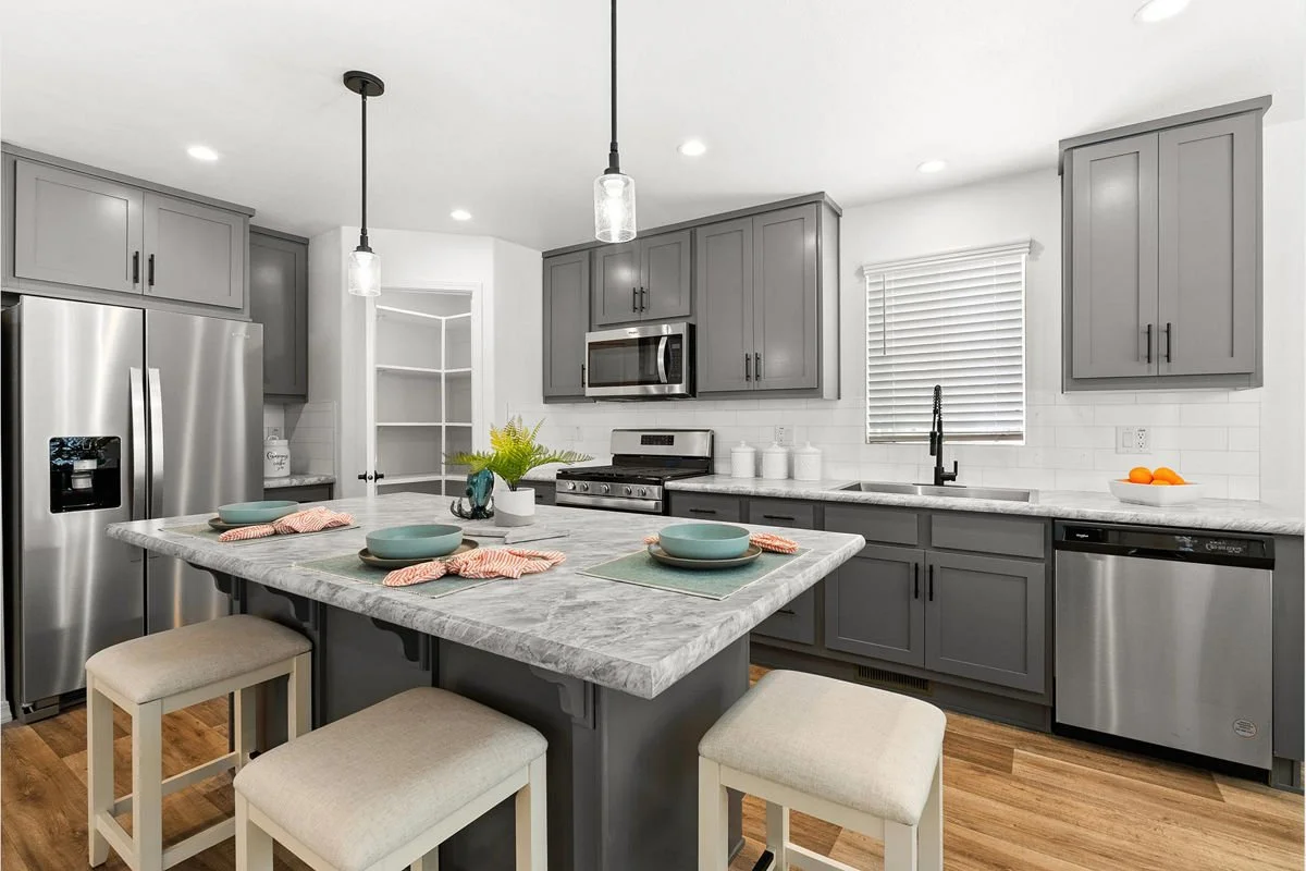 Modern kitchen with gray cabinets, stainless steel appliances, a marble island, and white subway tile backsplash.