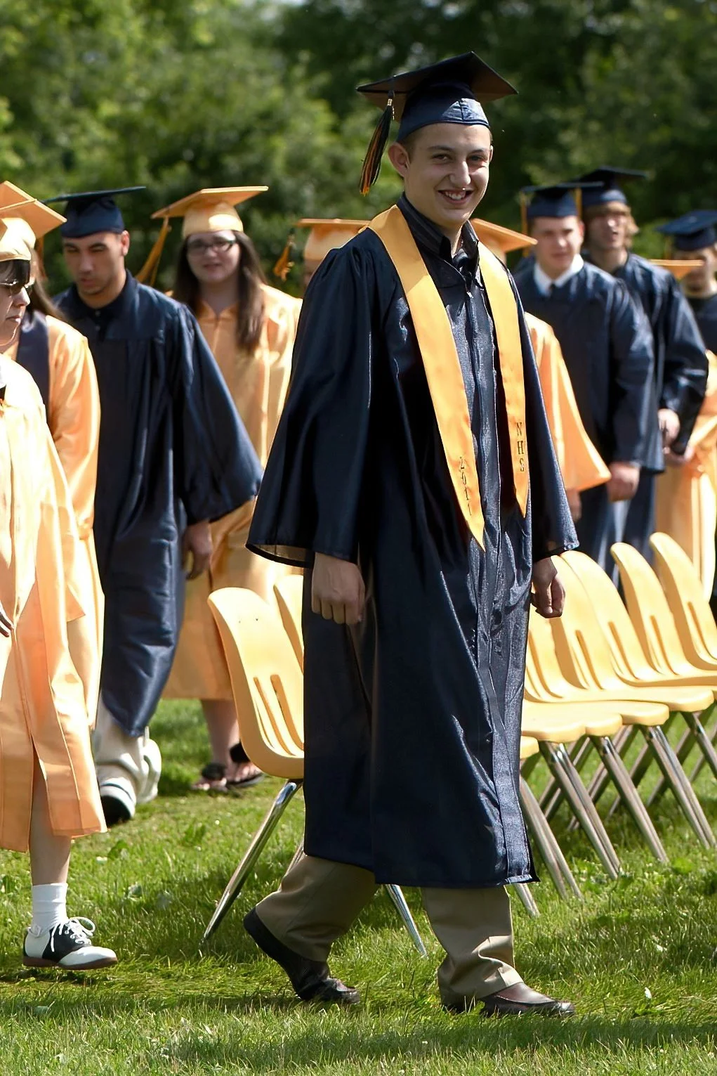 Group of students in graduation caps and gowns during outdoor graduation ceremony.