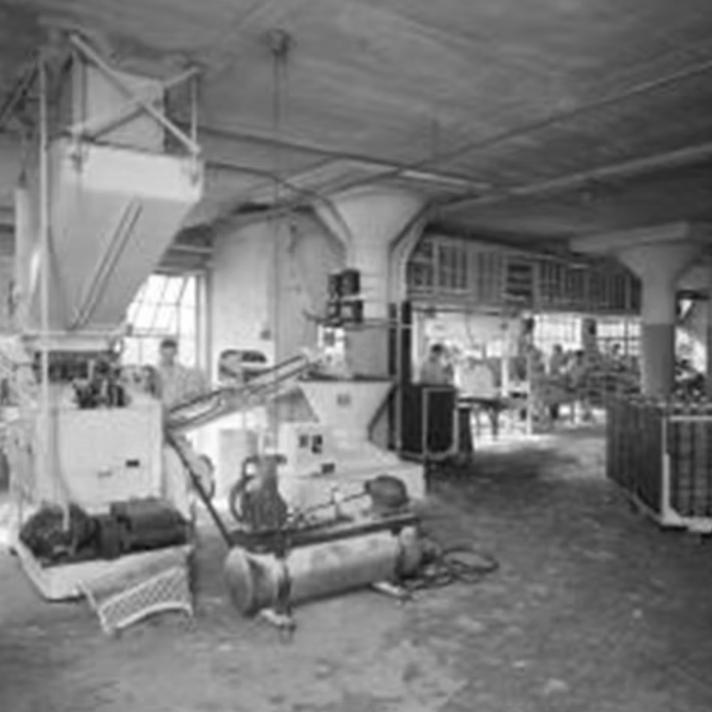 An industrial or warehouse space with machines, equipment, and workers in a large open area.