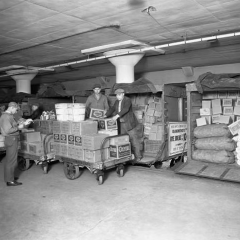 People working at a warehouse or storage facility with boxes and packages stacked around.