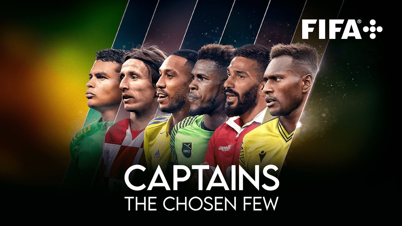 Six diverse male soccer players, dressed in team jerseys, standing in a line with serious expressions, with the FIFA logo and the text 'Captains: The Chosen Few' behind them.