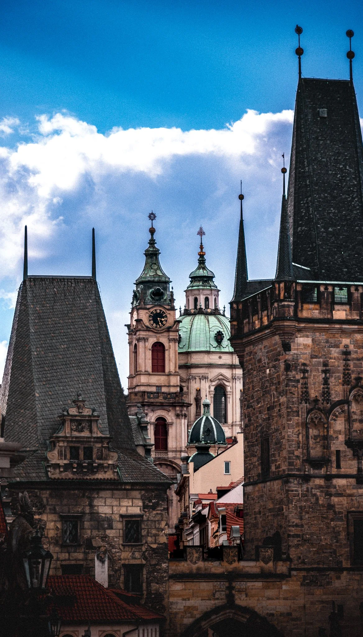 View of historic European-style church and castle towers with spires under a blue sky with clouds.