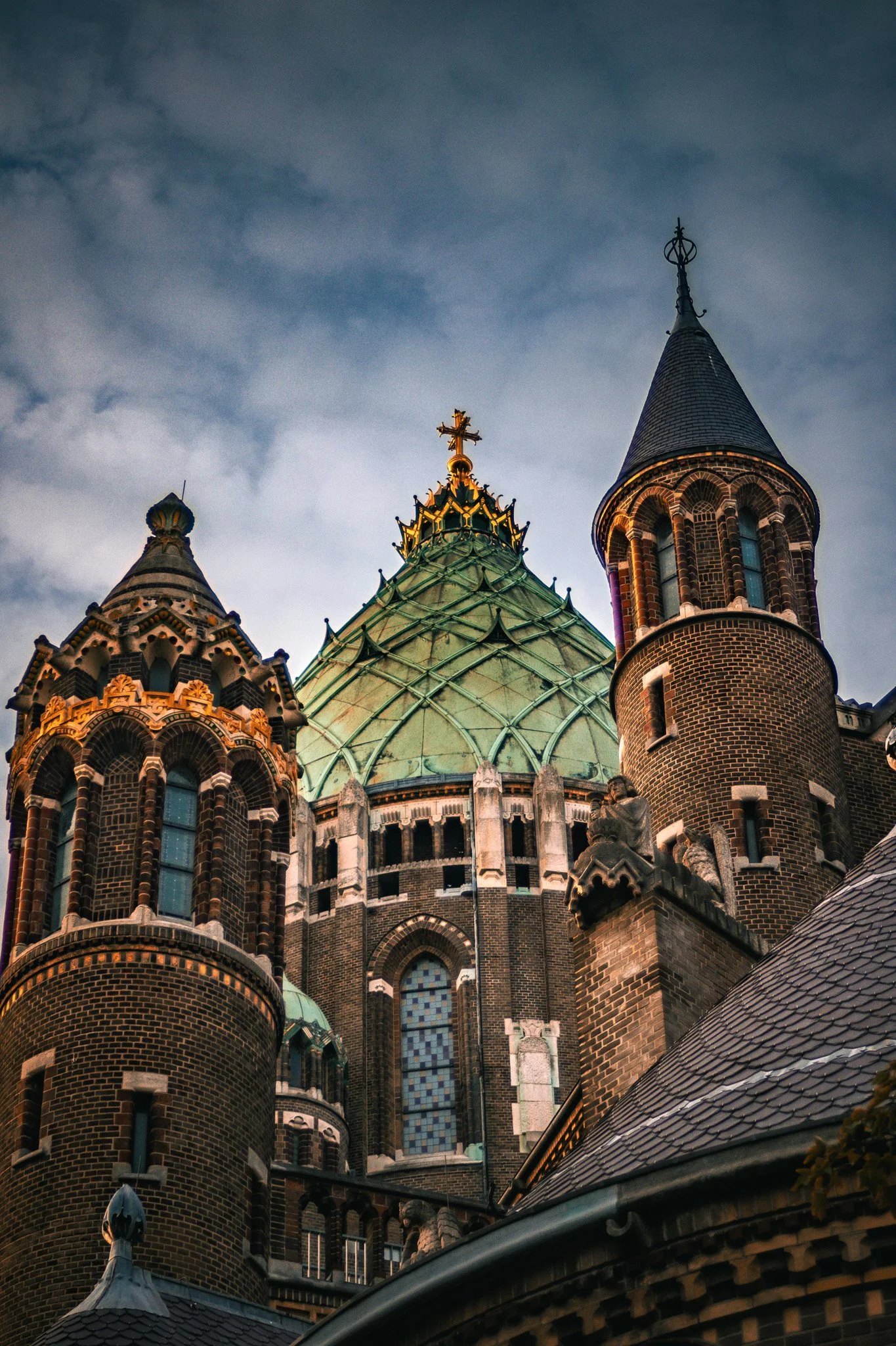 Close-up view of the spires and towers of a historic Gothic-style castle or church, with a cloudy sky in the background.