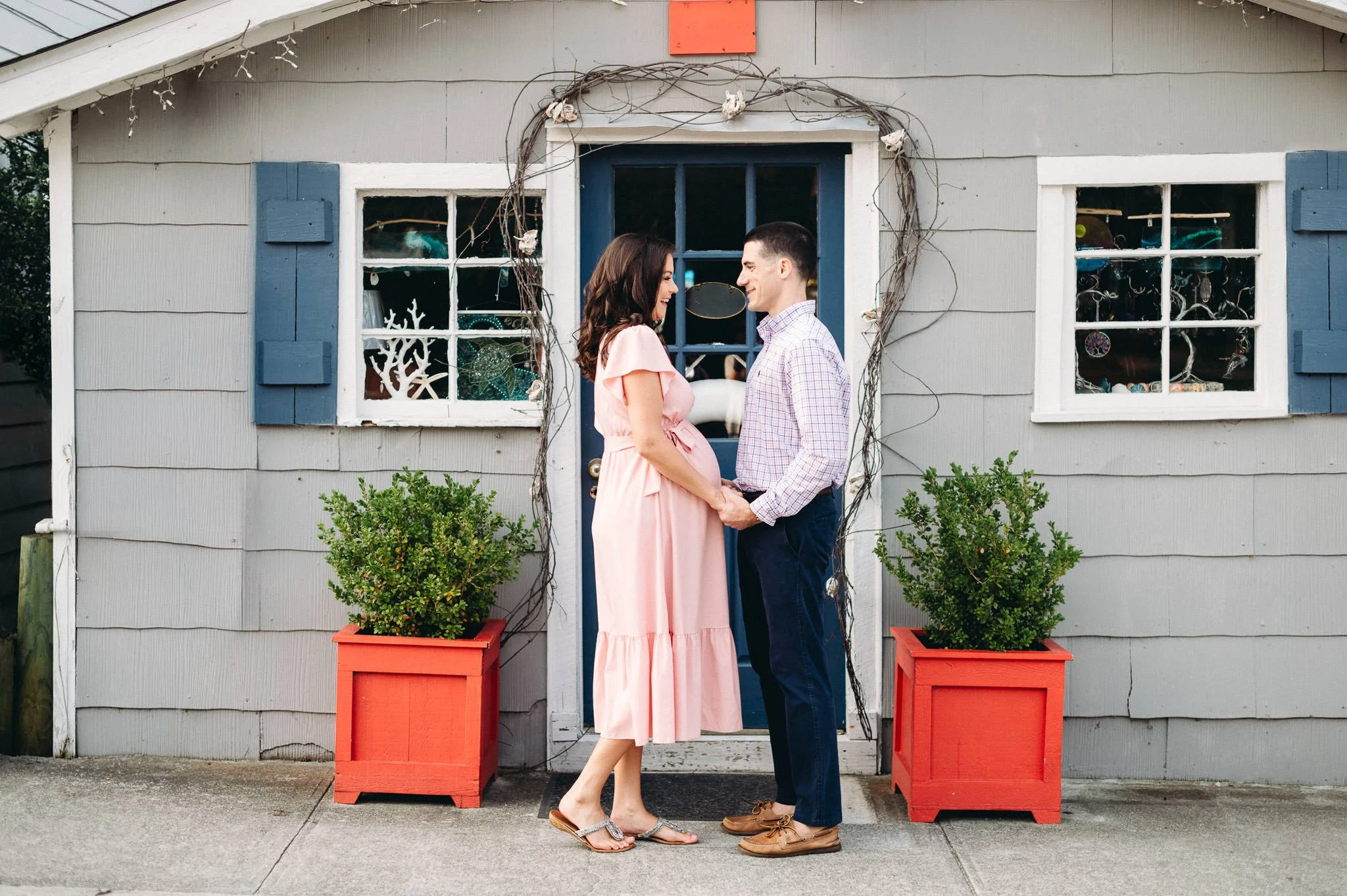 Pregnant wife and husband holding hands in front of a cute house, example of early morning best time for maternity photoshoot by Elise Souders, Bend photographer