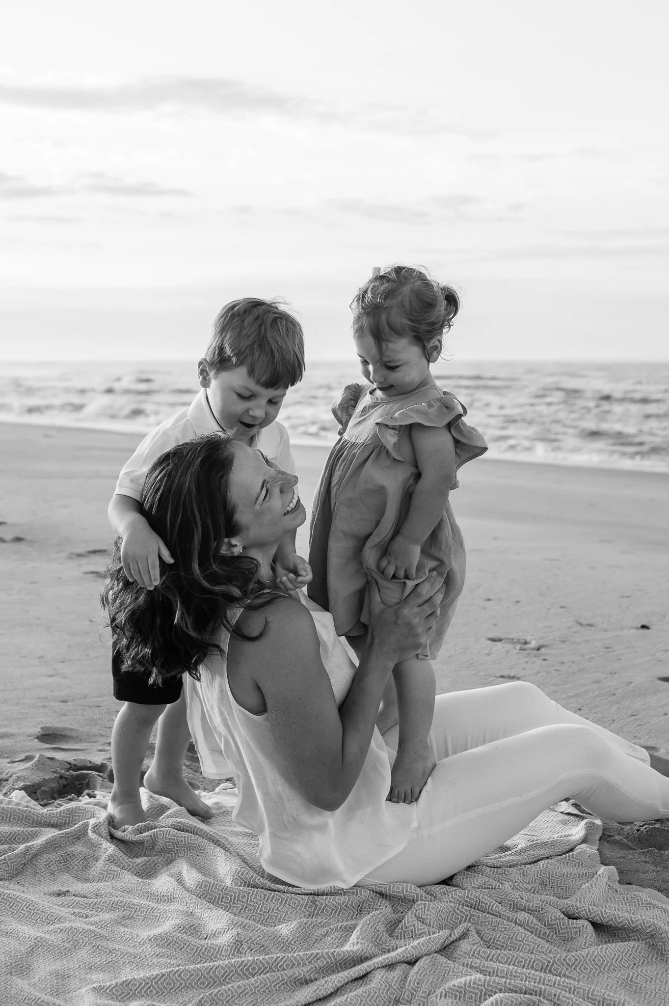 Mother and toddlers playing together on a beach for lifestyle family photos, by Elise Souders, photographer.