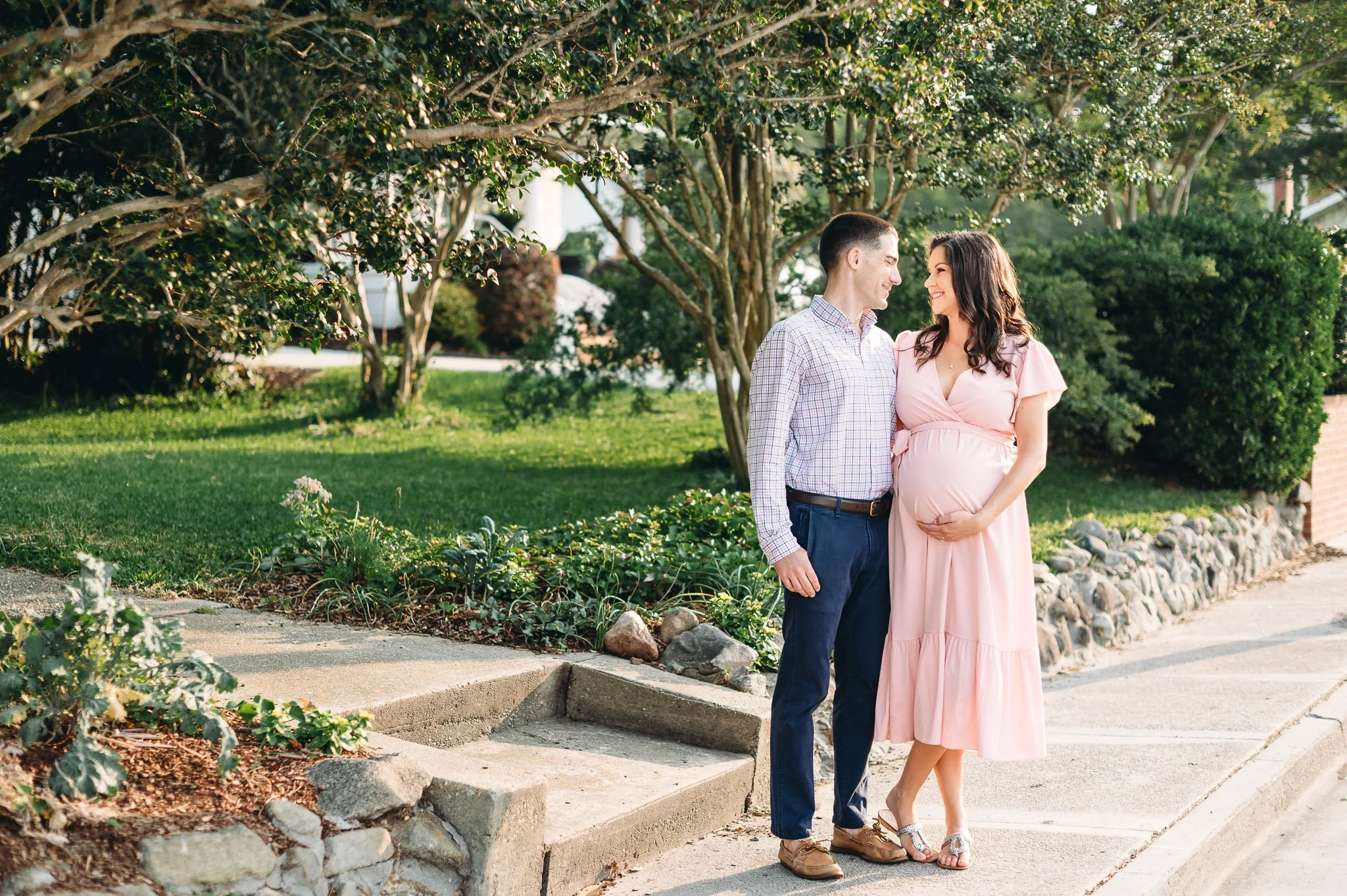 Husband and wife expecting a baby, standing in a neighborhood garden in early morning light in Central Oregon by Elise Souders Photography
