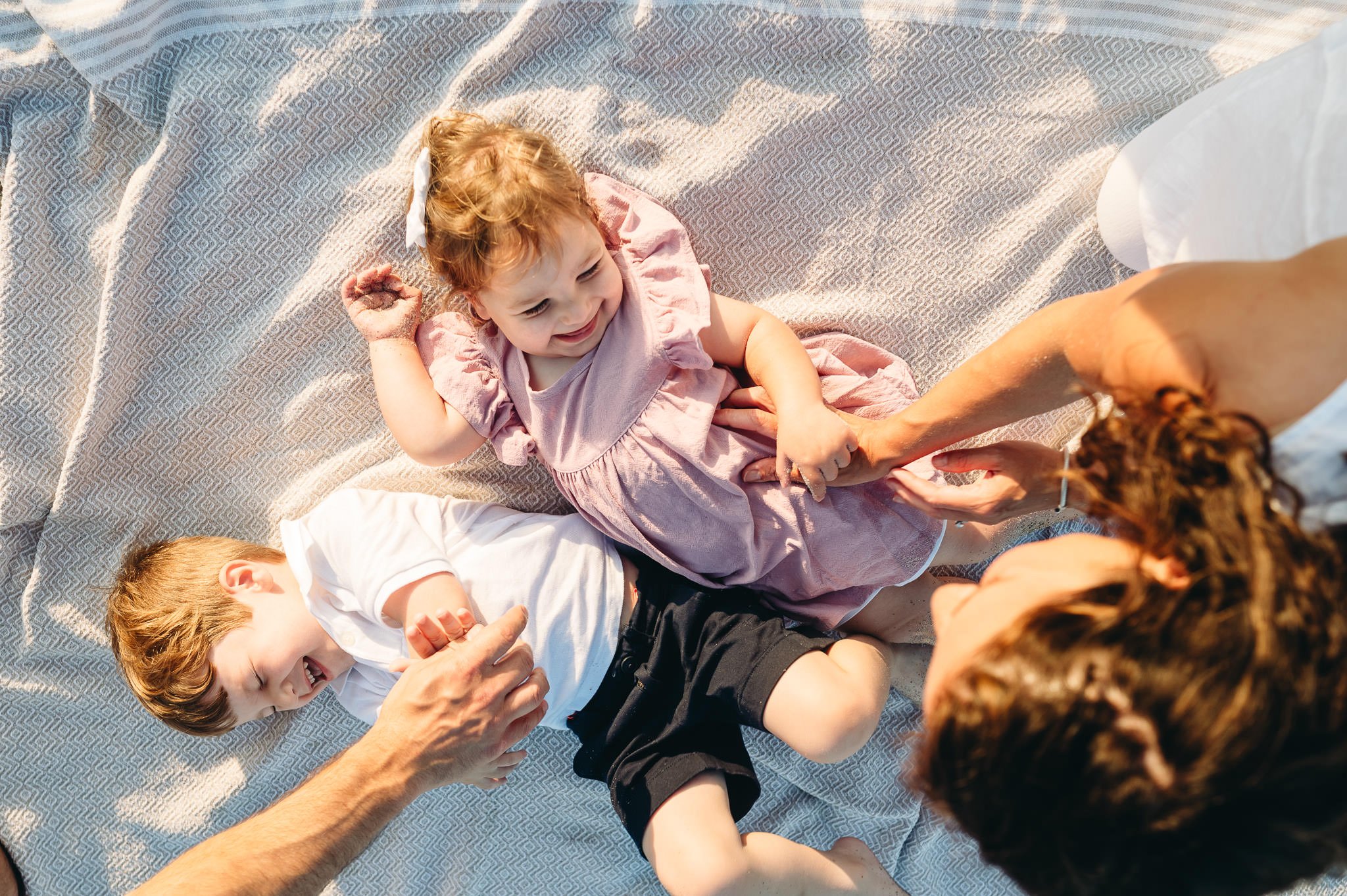 Joyful family portrait laughing on a blanket in Bend, Oregon by Elise Souders