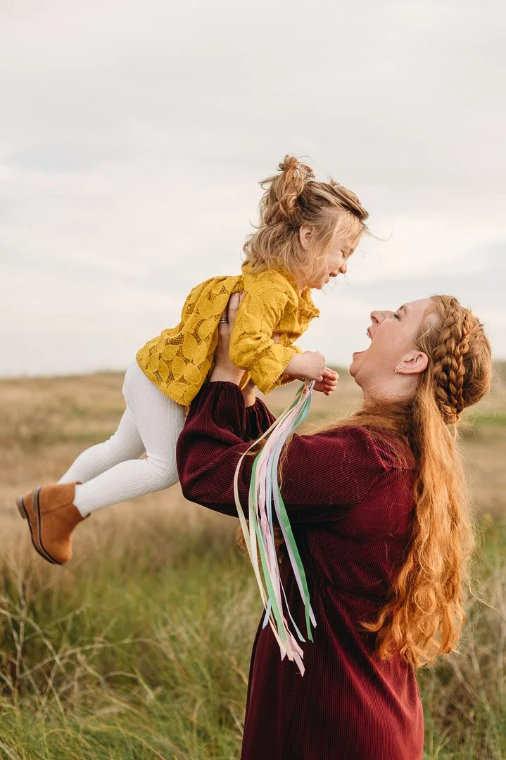 Mom lifting toddler girl in coordinated fall photo outfits in Bend, Oregon