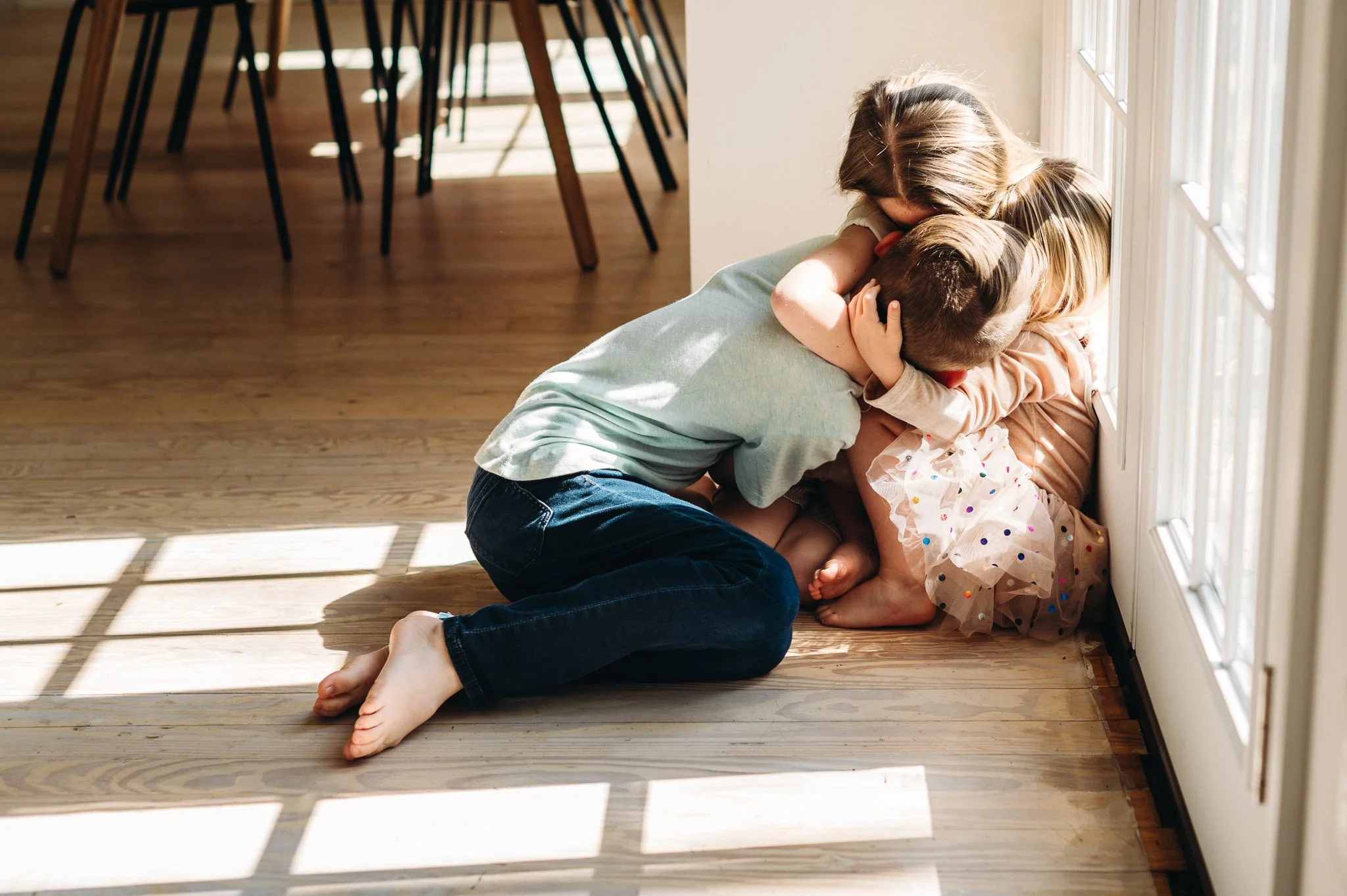 Children cuddled close in a splash of bright window light, photograph by Elise Souders, Bend Family Photographer