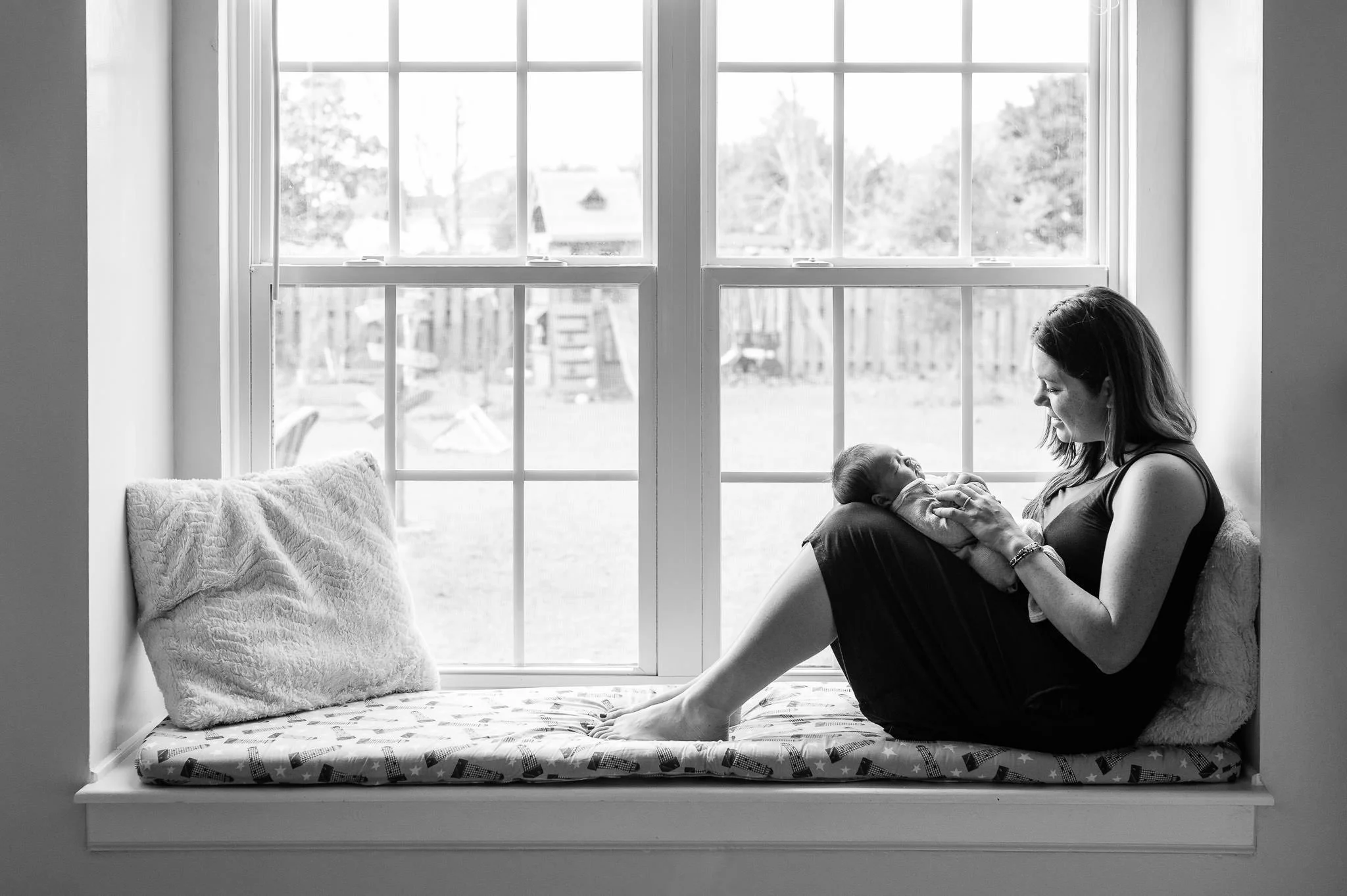 Black and white image of mother holding newborn baby by a large window, newborn photos by Elise Souders, Bend Oregon photographer