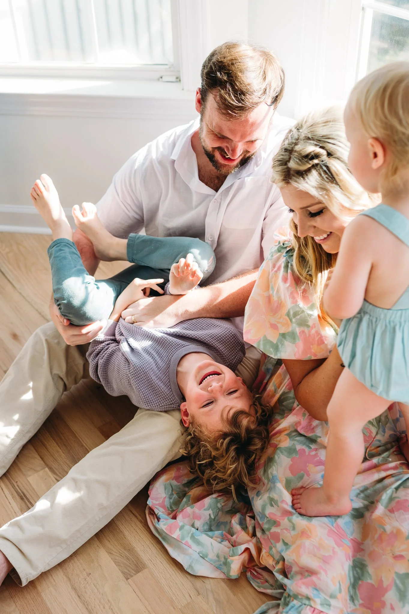 Family playing with children indoors, enjoying a joyful moment on the floor near a window lifestyle family photography in Central Oregon.