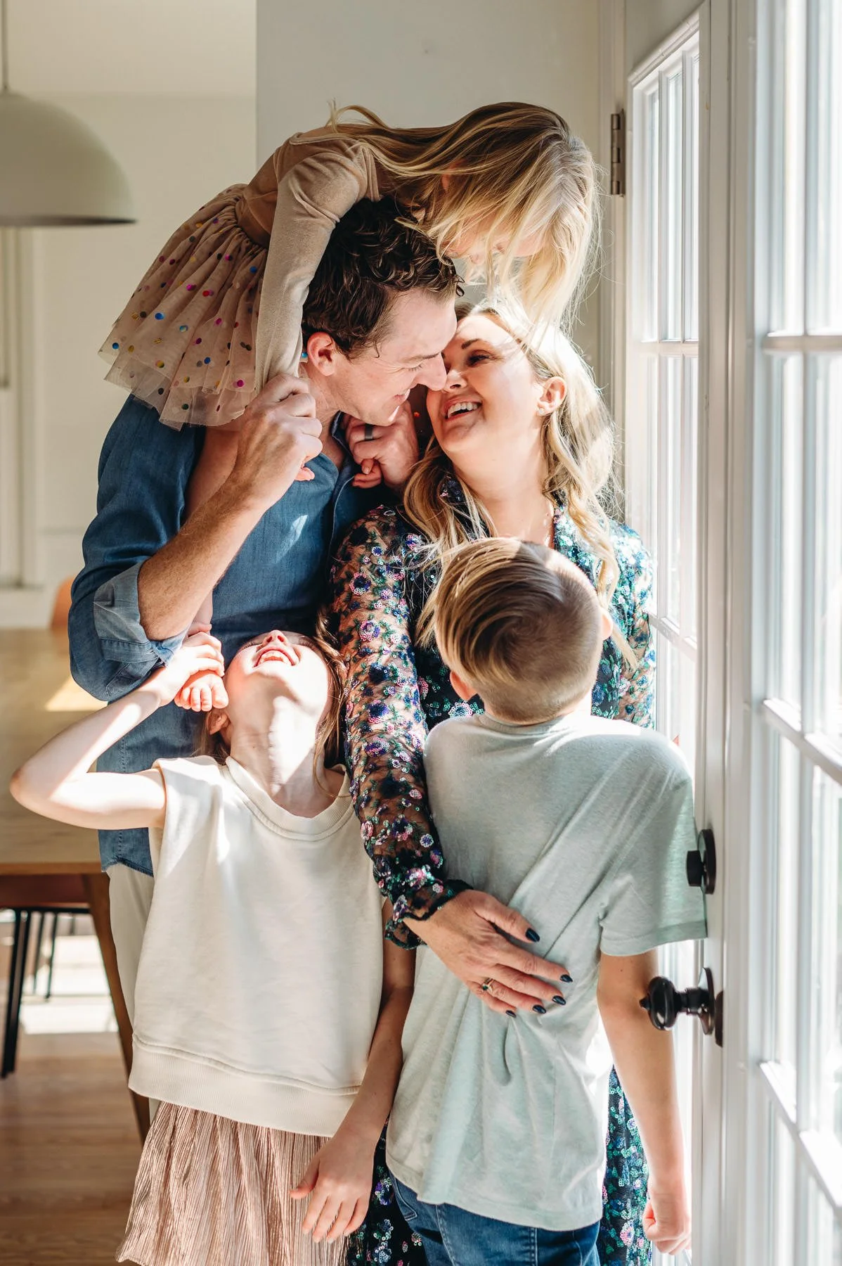 Three kids piled around mom and dad, all laughing together in genuine emotion. Photo by Elise Souders, Bend Family Photographer