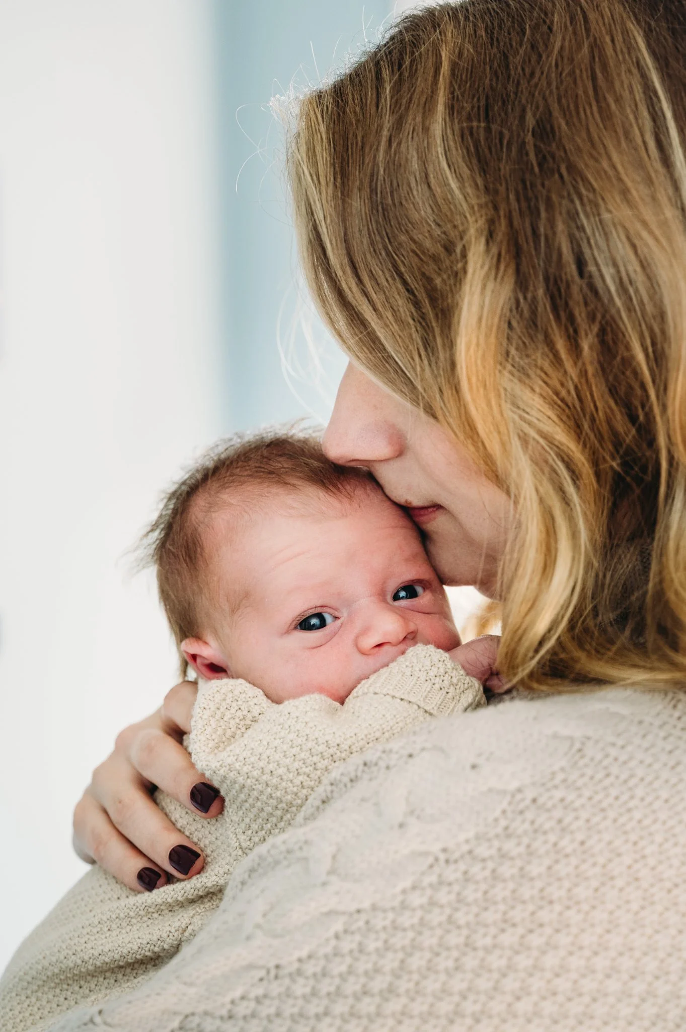 Mother holding newborn during in-home photo session in Bend, Oregon by Elise Souders