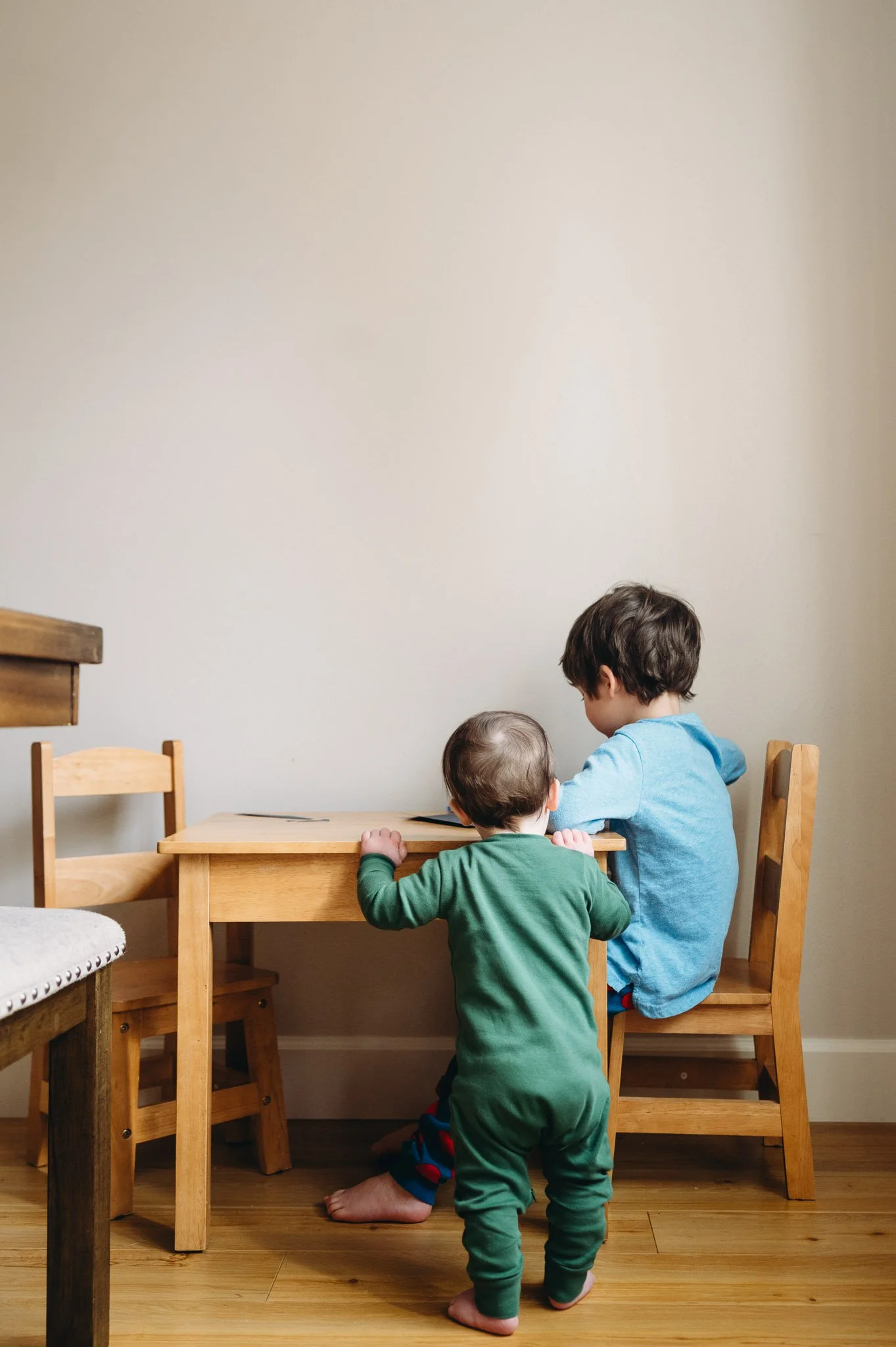 Two young children with short brown hair at a small child's table involved in an activity in documentary family photo by Elise Souders Photography.
