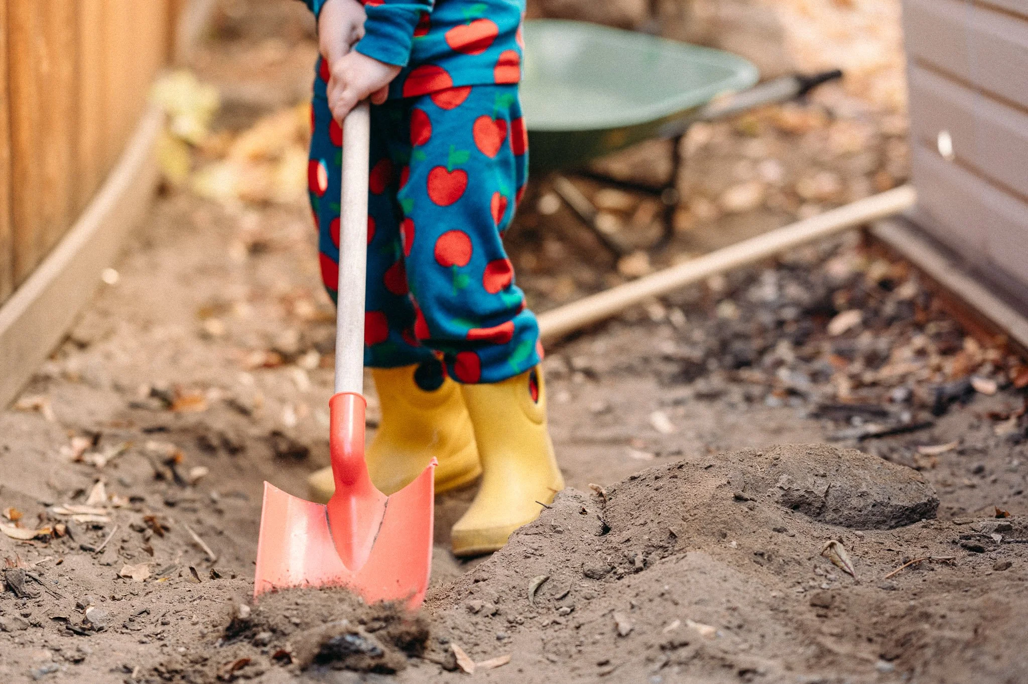 Preschooler digging in backyard with favorite yellow rainboots, documentary photograph by Elise Souders, Bend, Oregon.