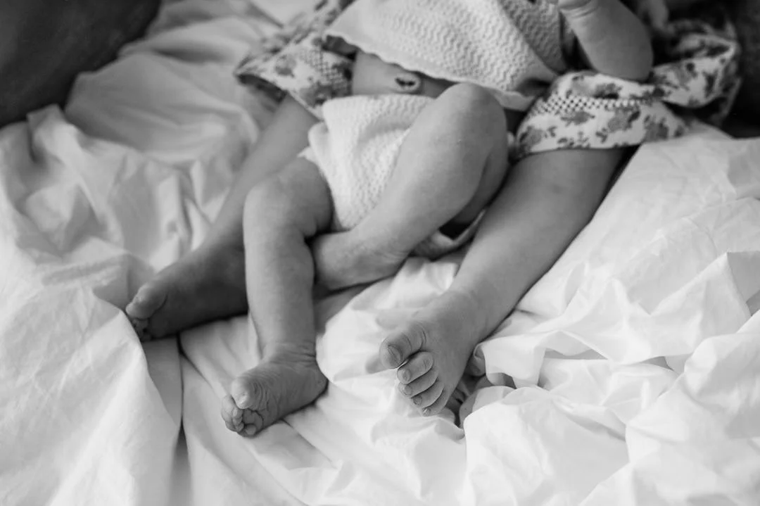 Toddler and newborn sibling feet entwined on bedsheets, newborn lifestyle photoshoot by Elise Souders, Bend Oregon photographer