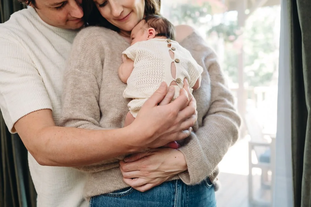 Mother and father cuddling baby during in-home newborn lifestyle photography session, Bend, Oregon.