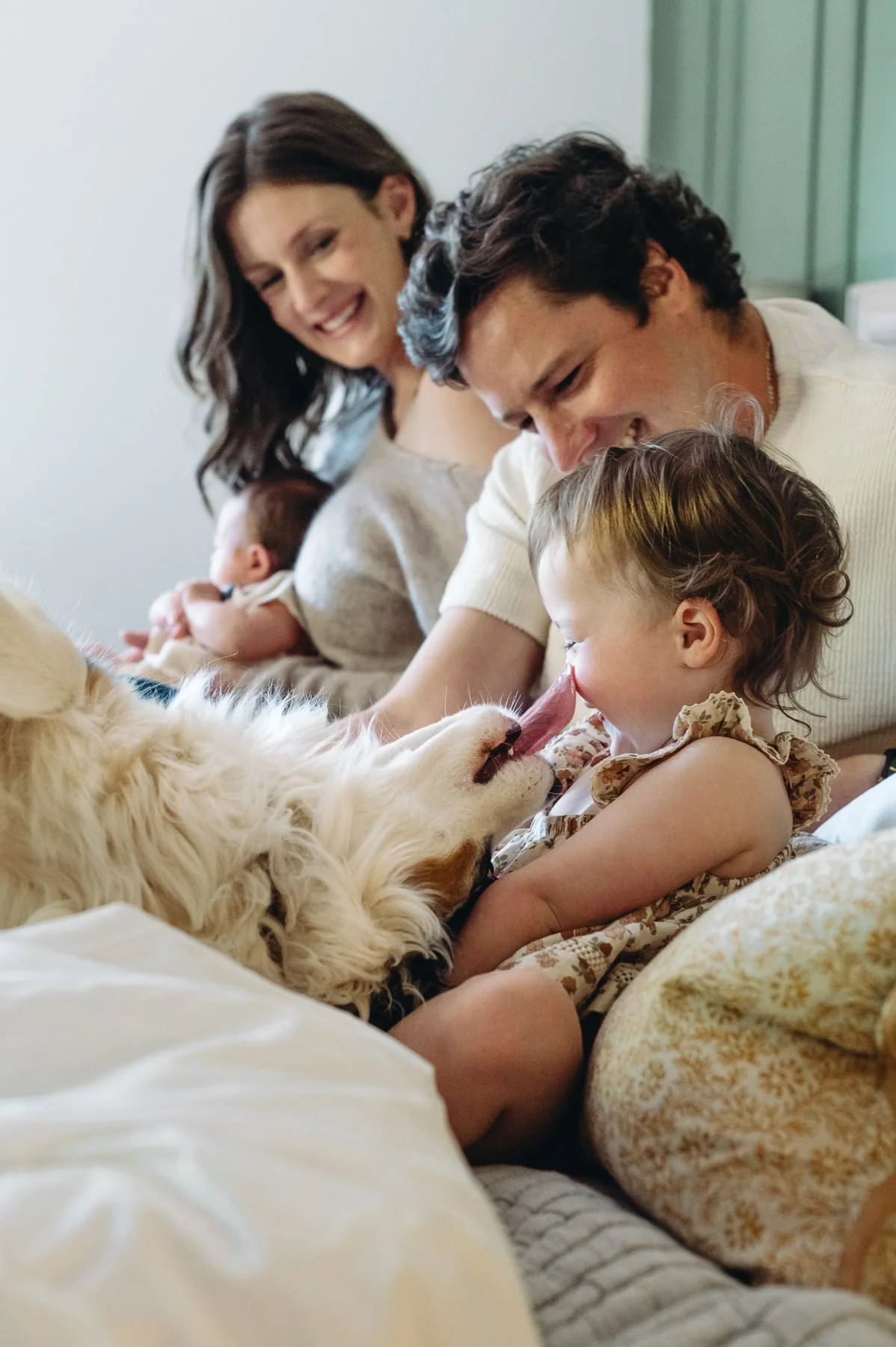 Dog licking child's face while family watching laughs, candid photo by Elise Souders, Bend, Oregon family photographer
