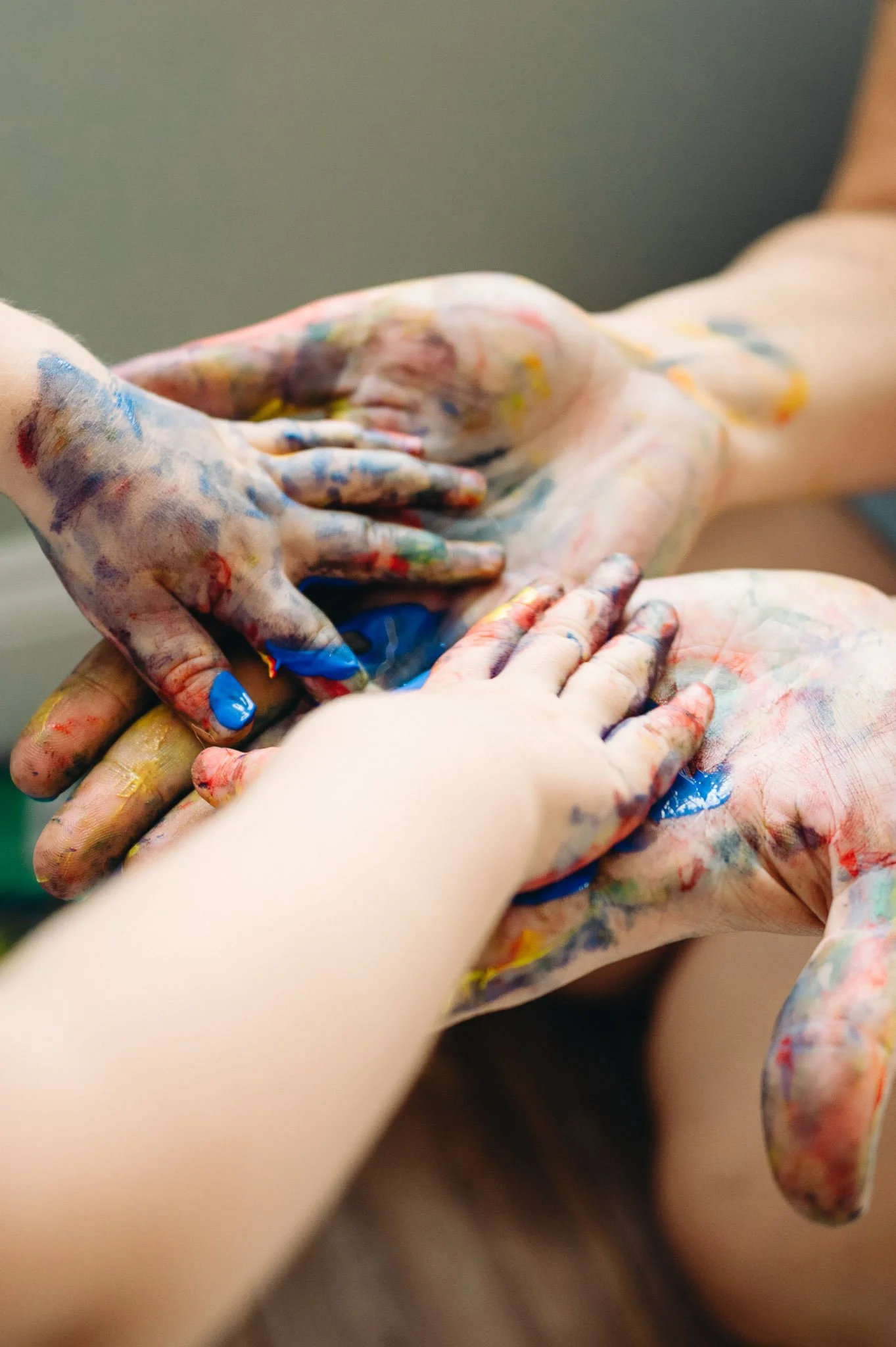 Mother and child's hands covered in colorful paint, layered together in an artistic arrangement for creative motherhood photoshoot by Elise Souders in Bend, Oregon.