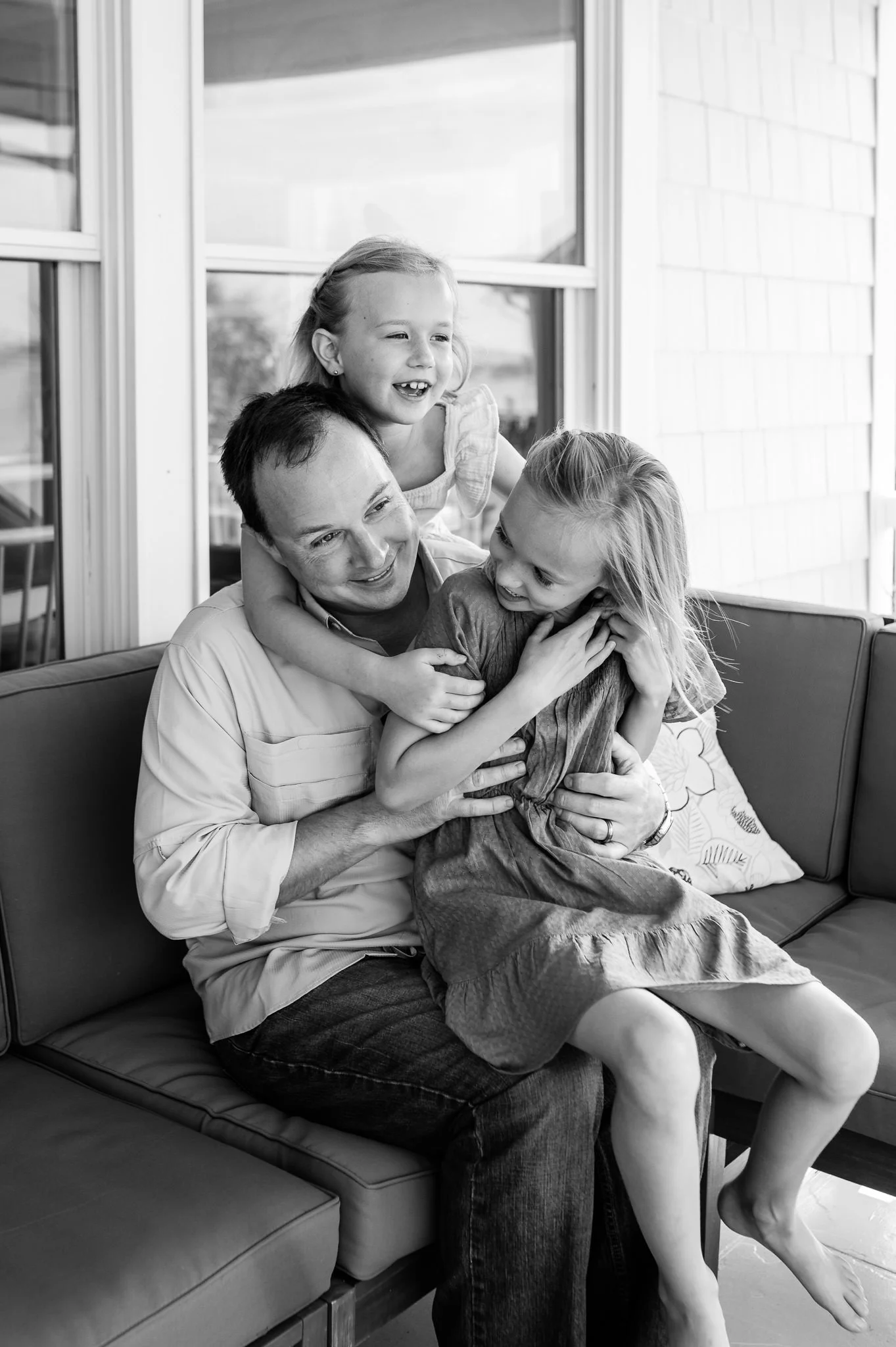father and two daughters laughing on their porch, family photography in Bend, Oregon by Elise Souders