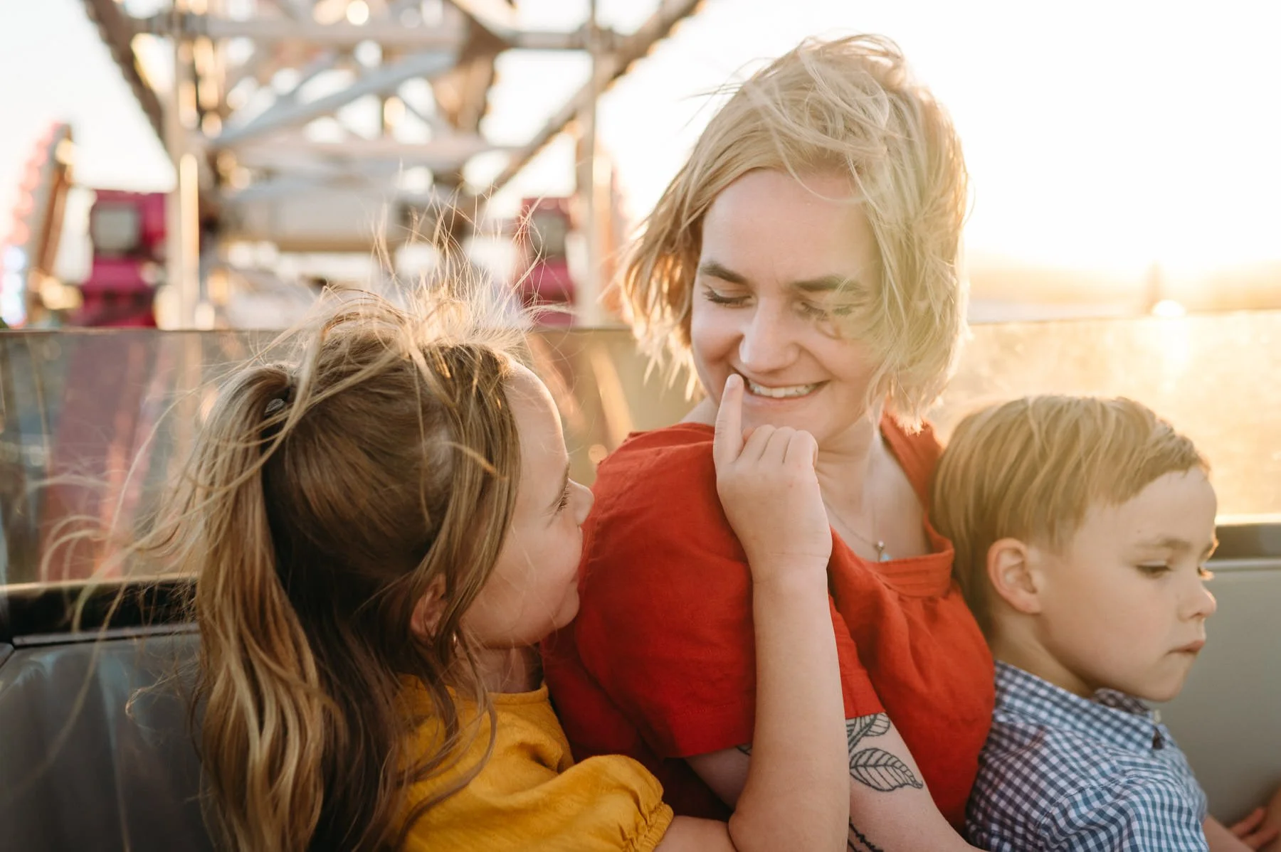 Mother and children riding the ferris wheel, daughter playfully poking at mother's nose. Photo by Elise Souders, Bend, OR photographer