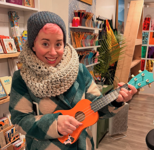 Woman in winter coat plays ukele in art store