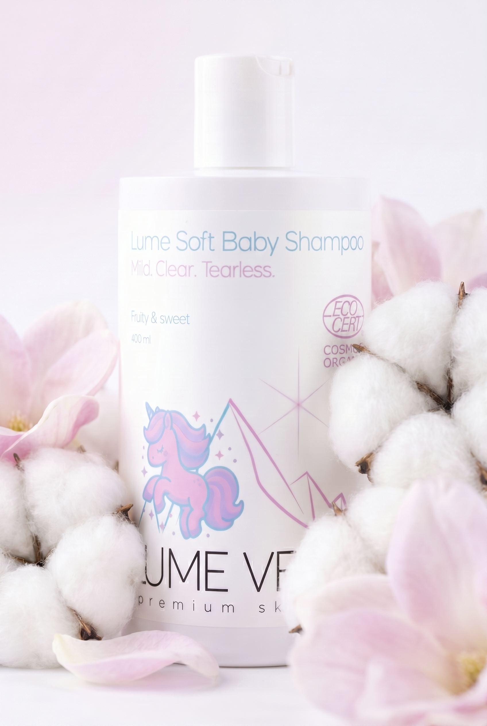 Ein Flaschenprodukt namens 'Lume Soft Baby Shampoo' auf weißem Hintergrund, umgeben von rosa Blütenblättern und Baumwollpflanzen, mit Texten 'Mild. Clear. Tearless', 'Fruity & sweet'.