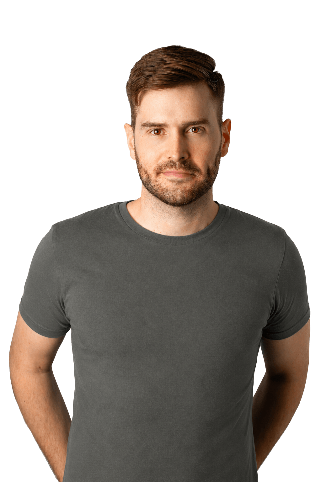 A man with brown hair and a beard wearing a dark gray t-shirt, standing with his hands behind his back against a black background.