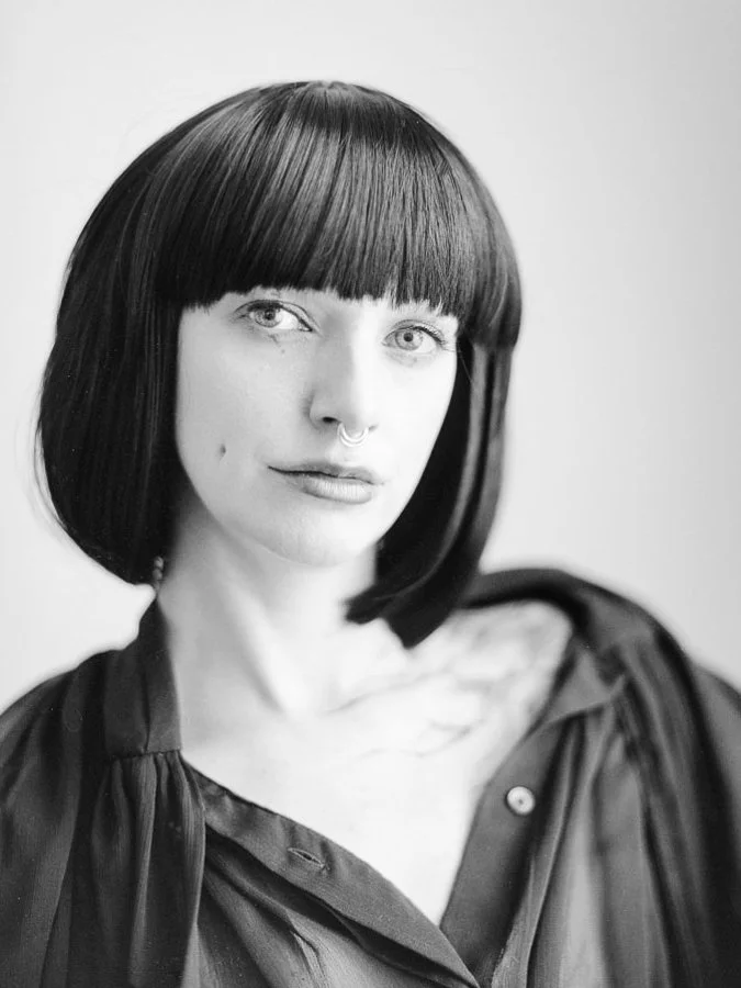 Black-and-white analogue portrait of Talli Lyndsey with a dark bob haircut, looking directly towards the camera.