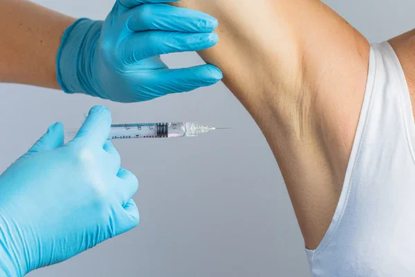 A medical professional administering a shot to a person's armpit