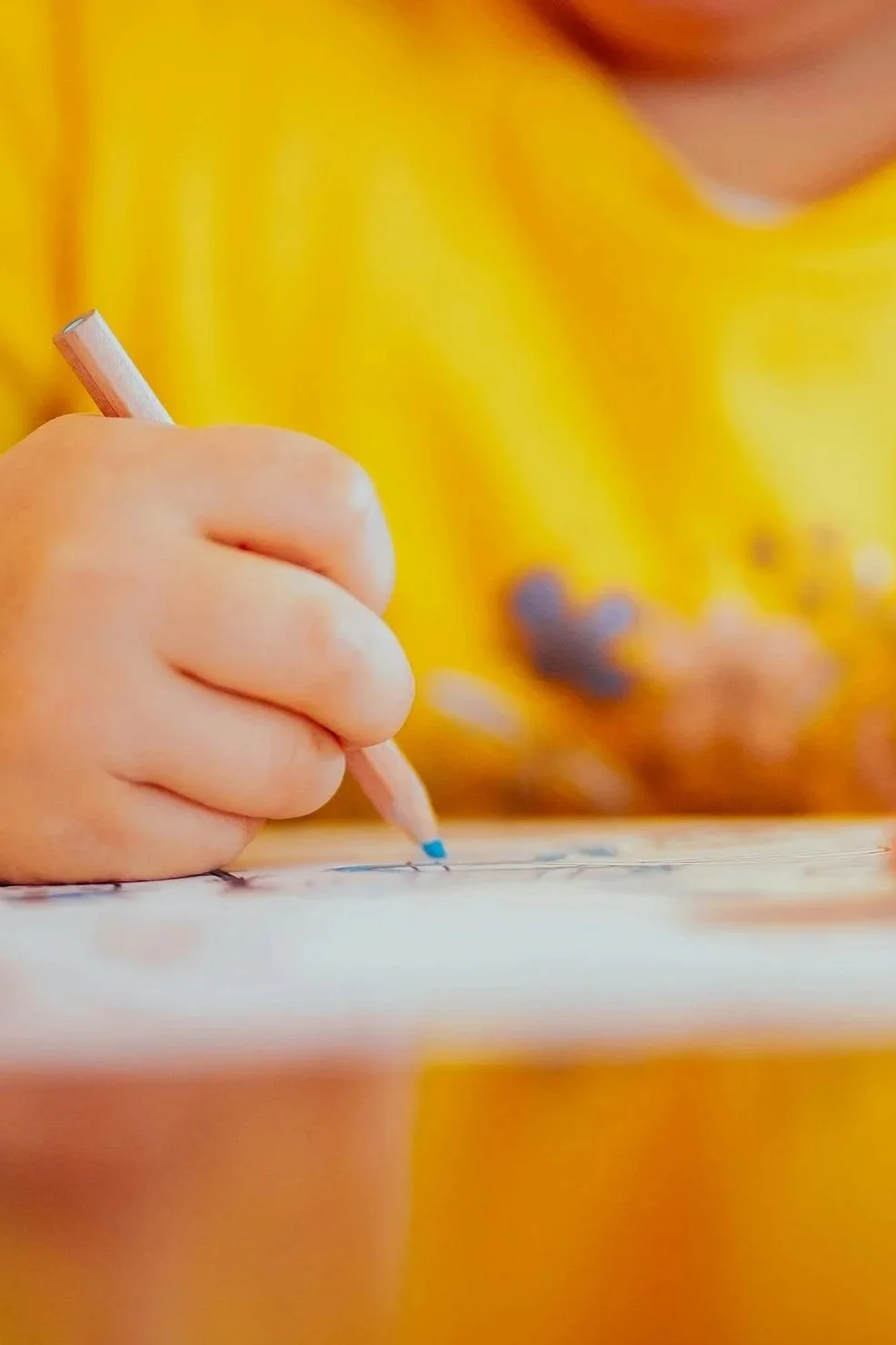 노란색 옷을 입은 어린 아이가 연필로 그림을 그리고 있는 모습