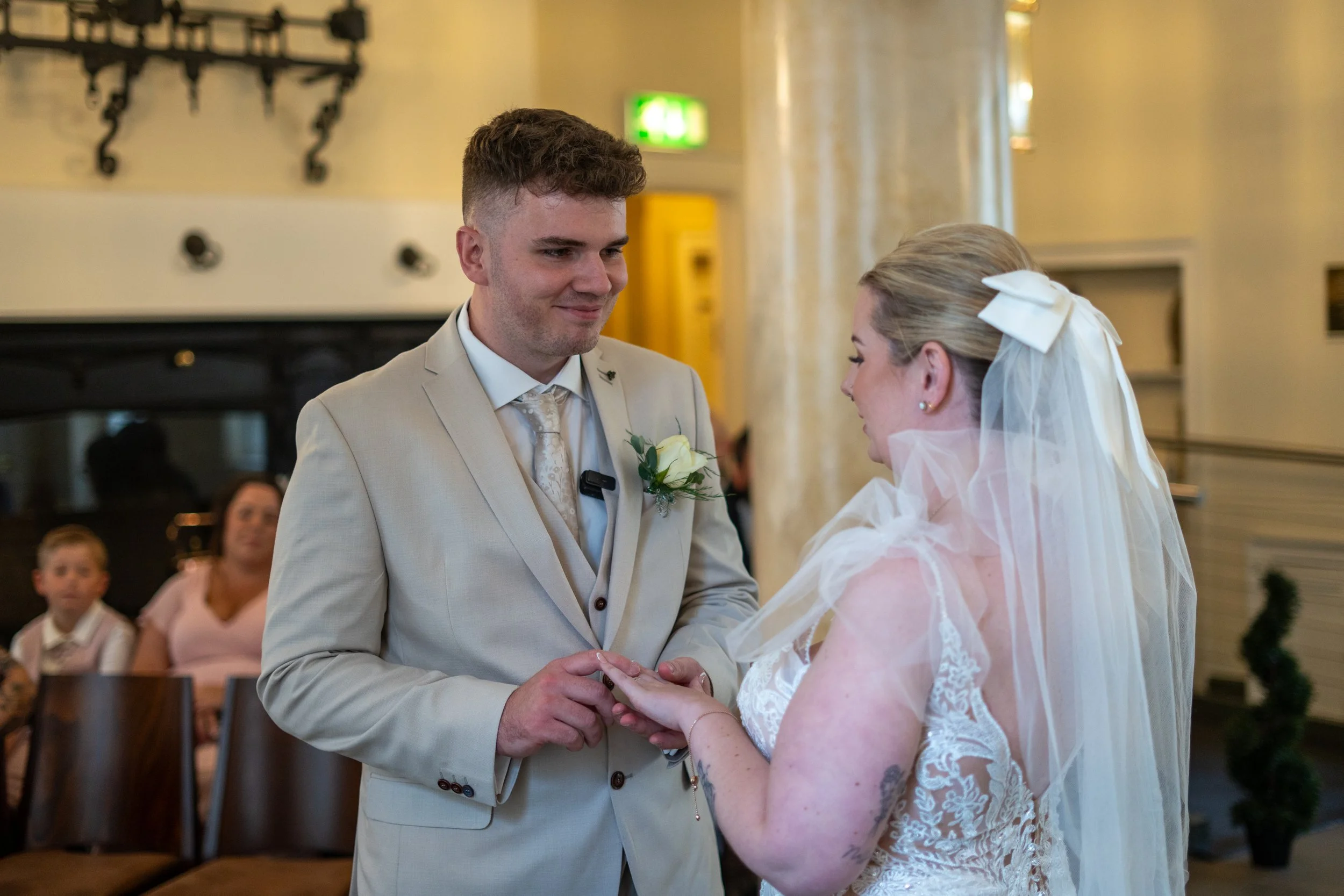 A couple holding hands during a wedding ceremony, with guests in the background.