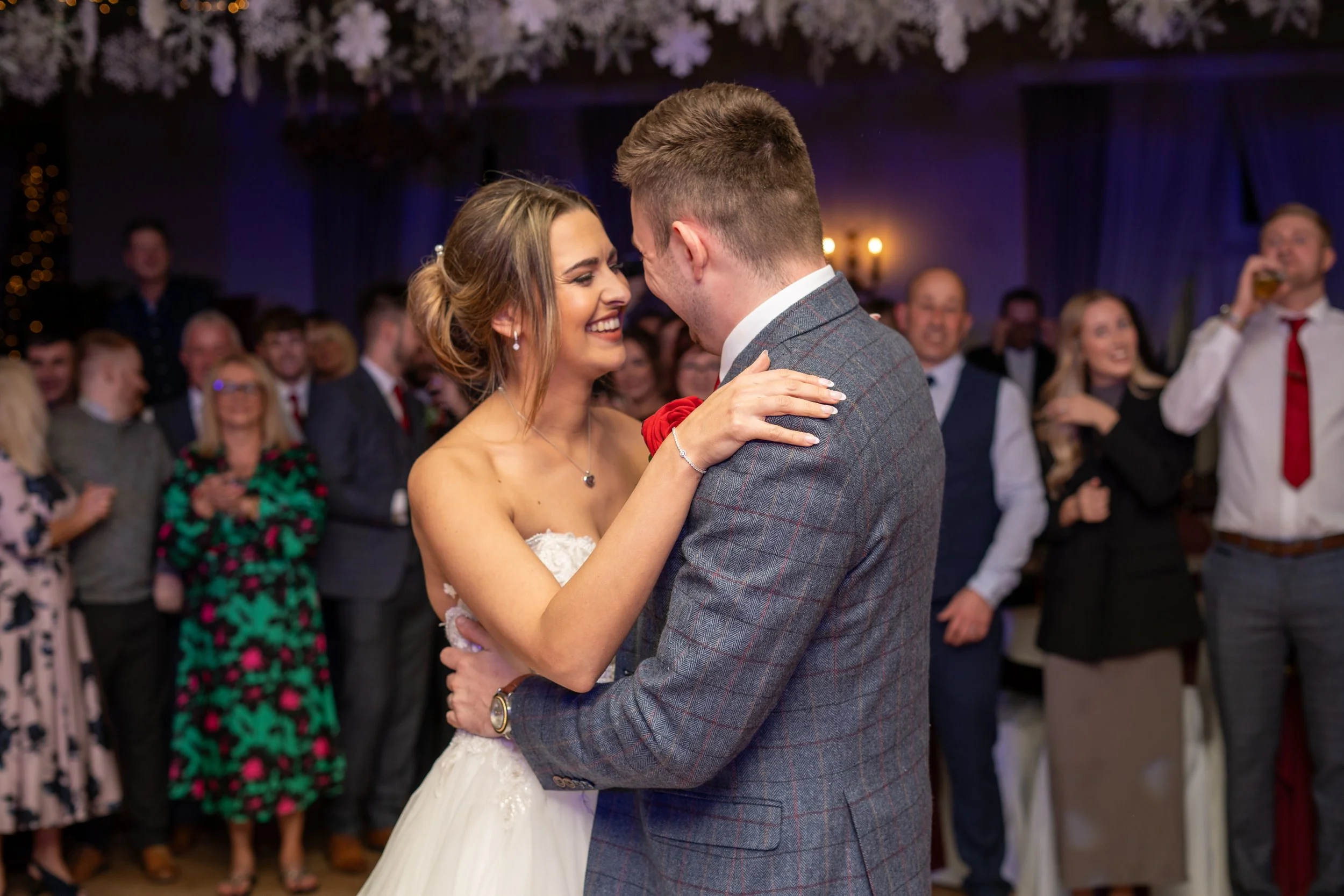 Bride and groom sharing a dance at their wedding reception, surrounded by guests.