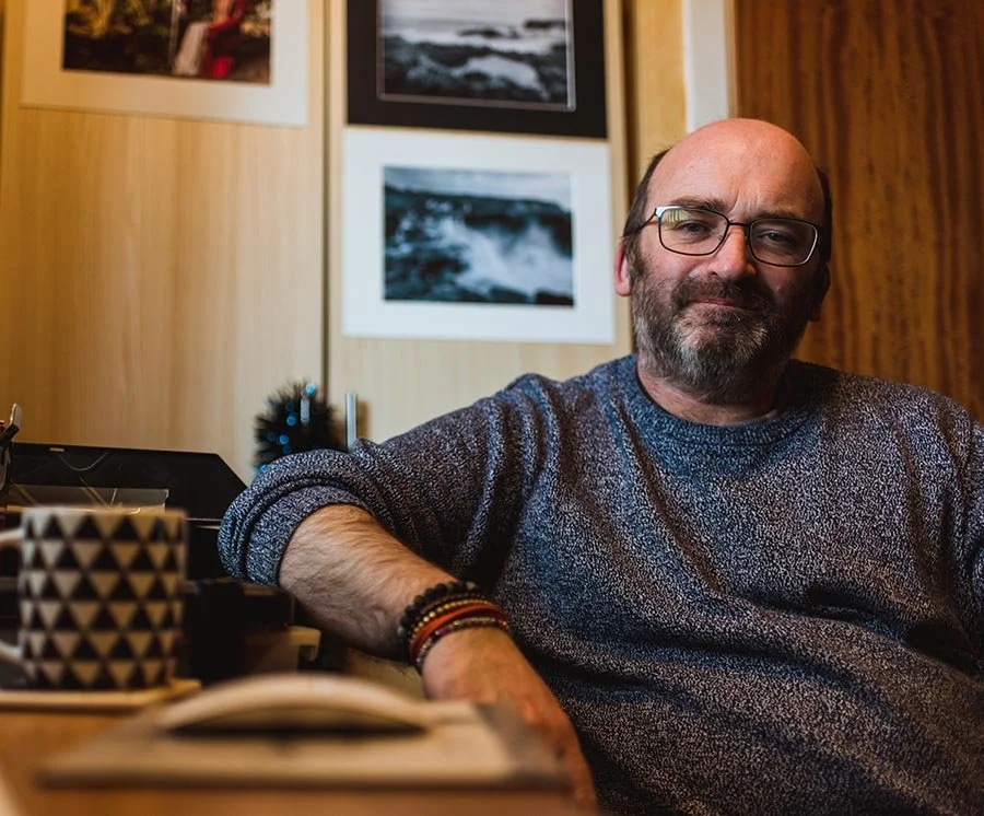 Philip sitting with arm on desk in the office.