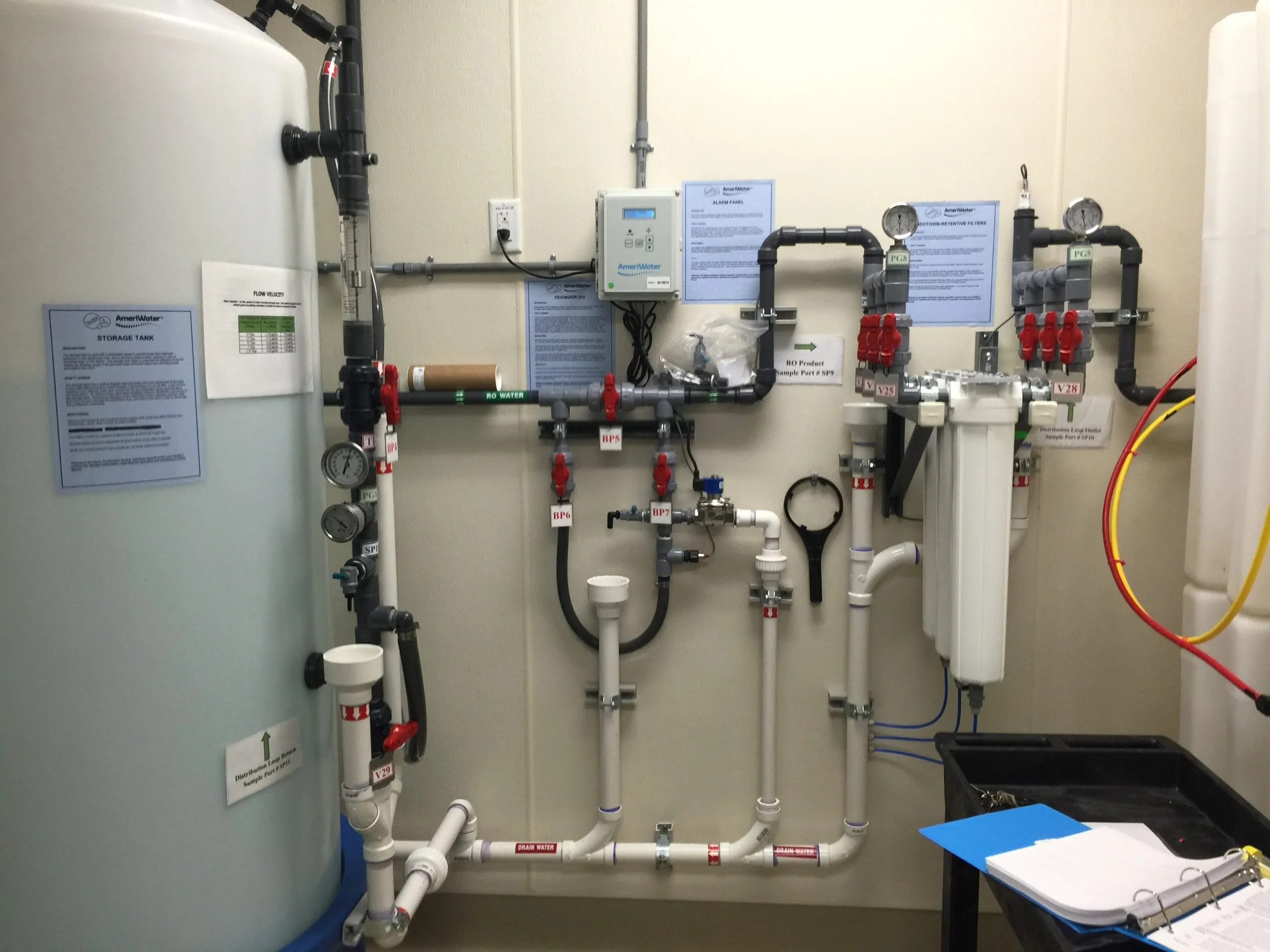 Industrial water filtration system with storage tank, pipes, gauges, and control panels.