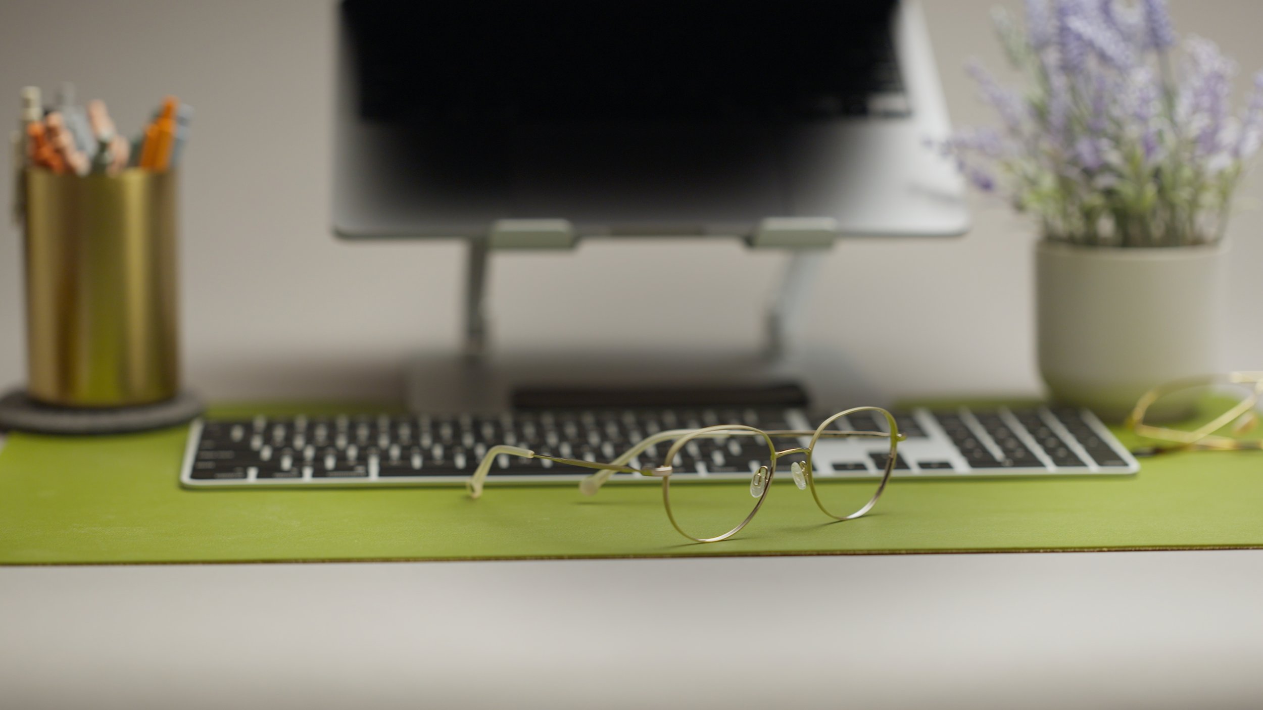 Glasses by a computer with desk supplies , lavender plant