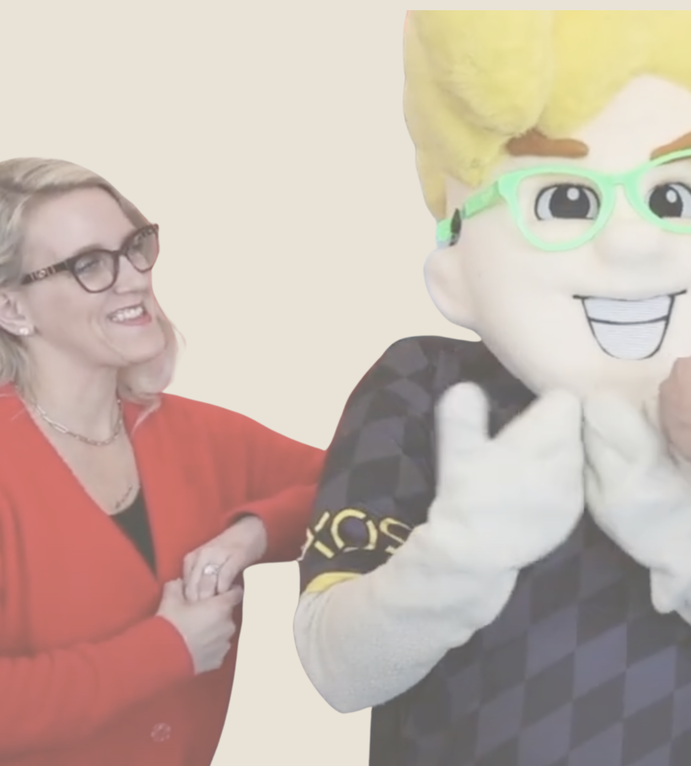 Blonde Haired woman wearing tortoise classes with gold jewelry and earrings, with Milwaukee Wave Mascott smiling he is wearing bright green glasses