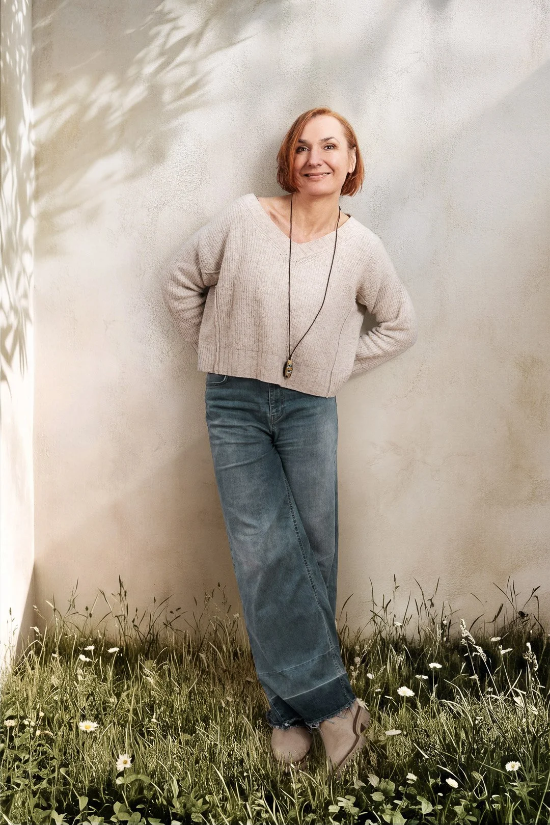 Petra lehnt an einer Hauswand und lächelt