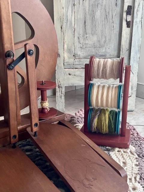 Particolare di una macchina per cucire vecchia e di uno stand con attrezzi di filato in vari colori, in una stanza con pareti di legno e un tappeto.